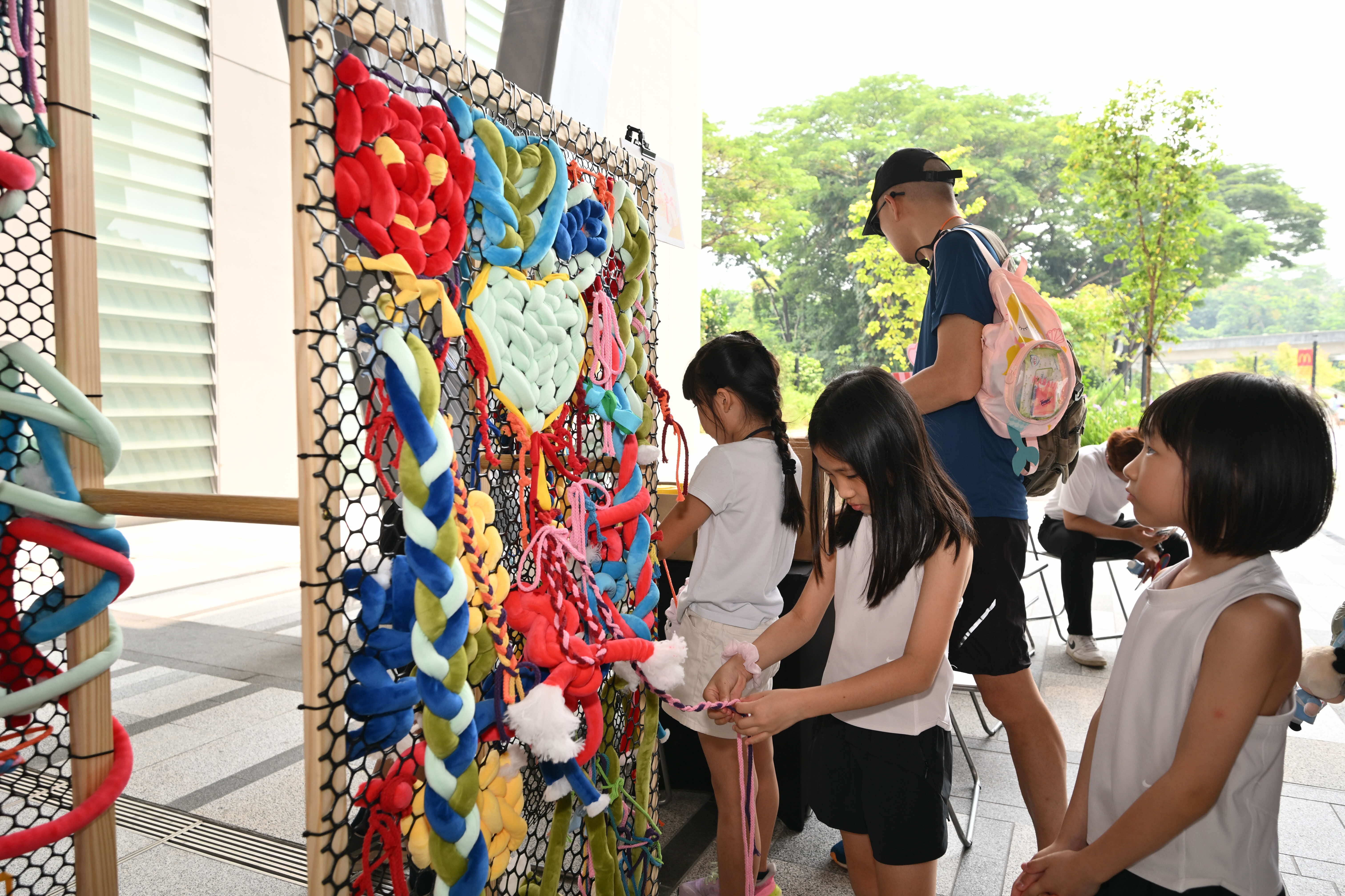Participants trying out the weaving activity using colourful strings to come up with one big collaborative art piece