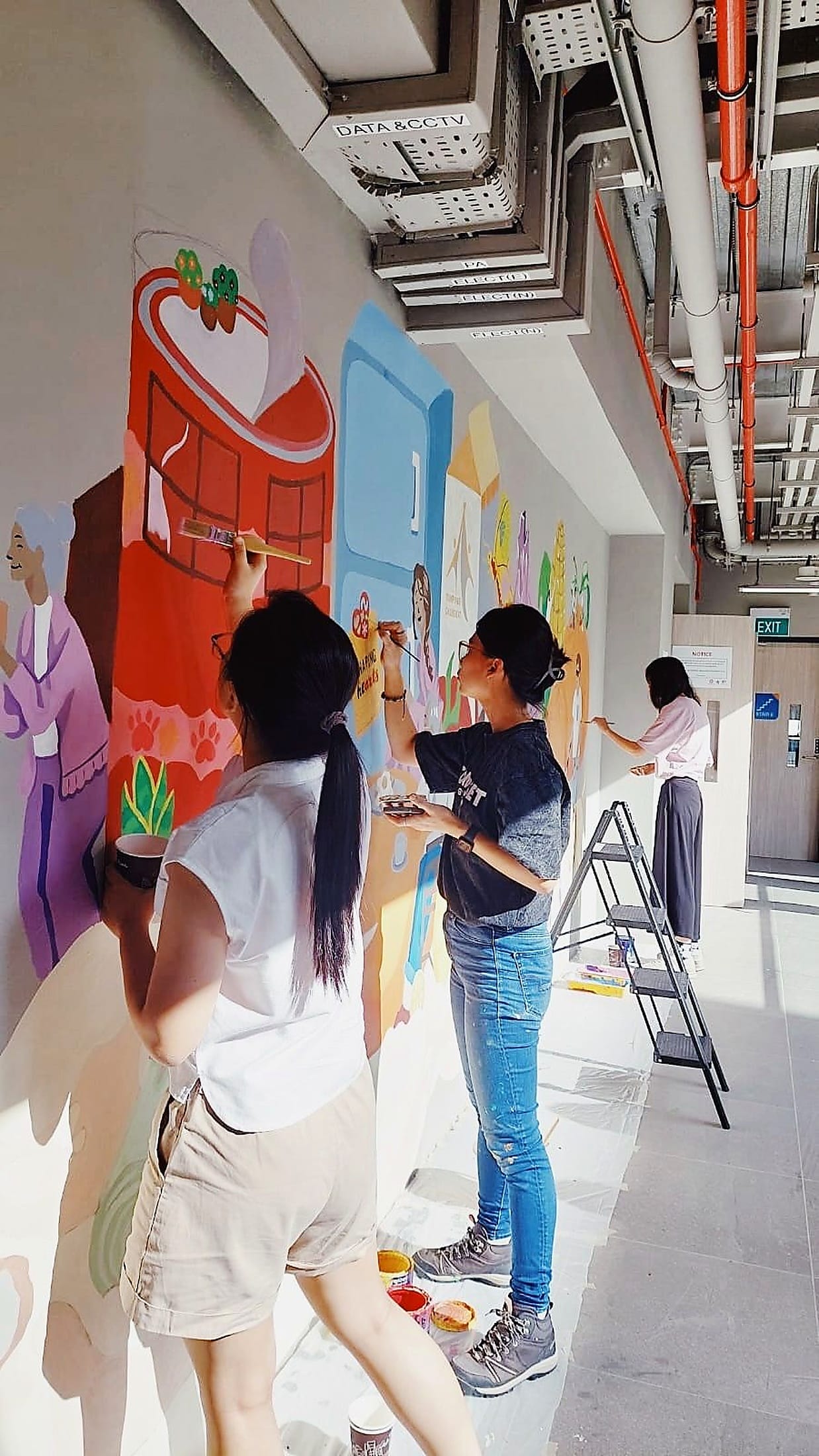 People painting the Edible Terrains mural wall at Tampines Changkat Community Club.