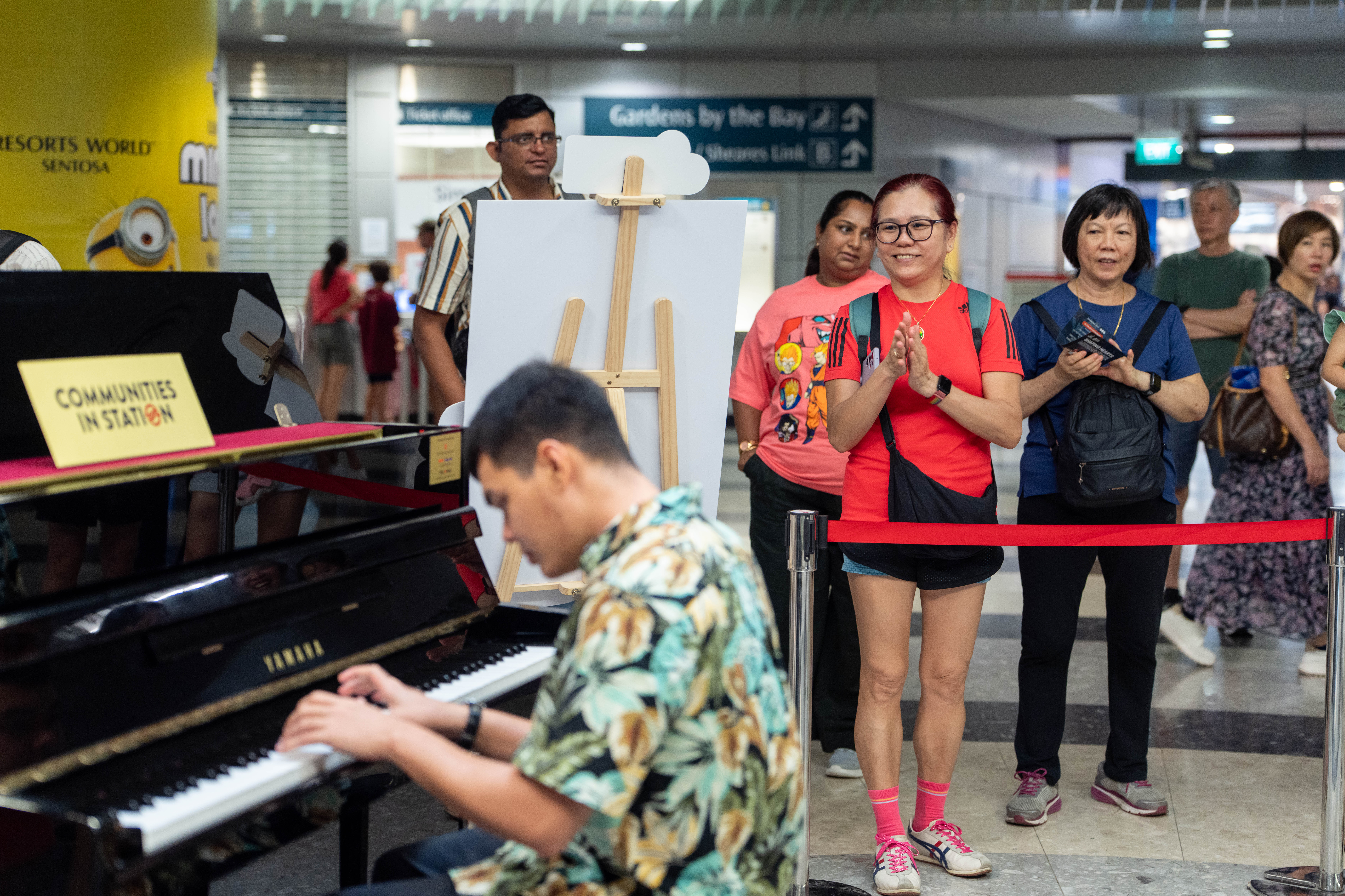 People stand and watch someone playing a piano.
