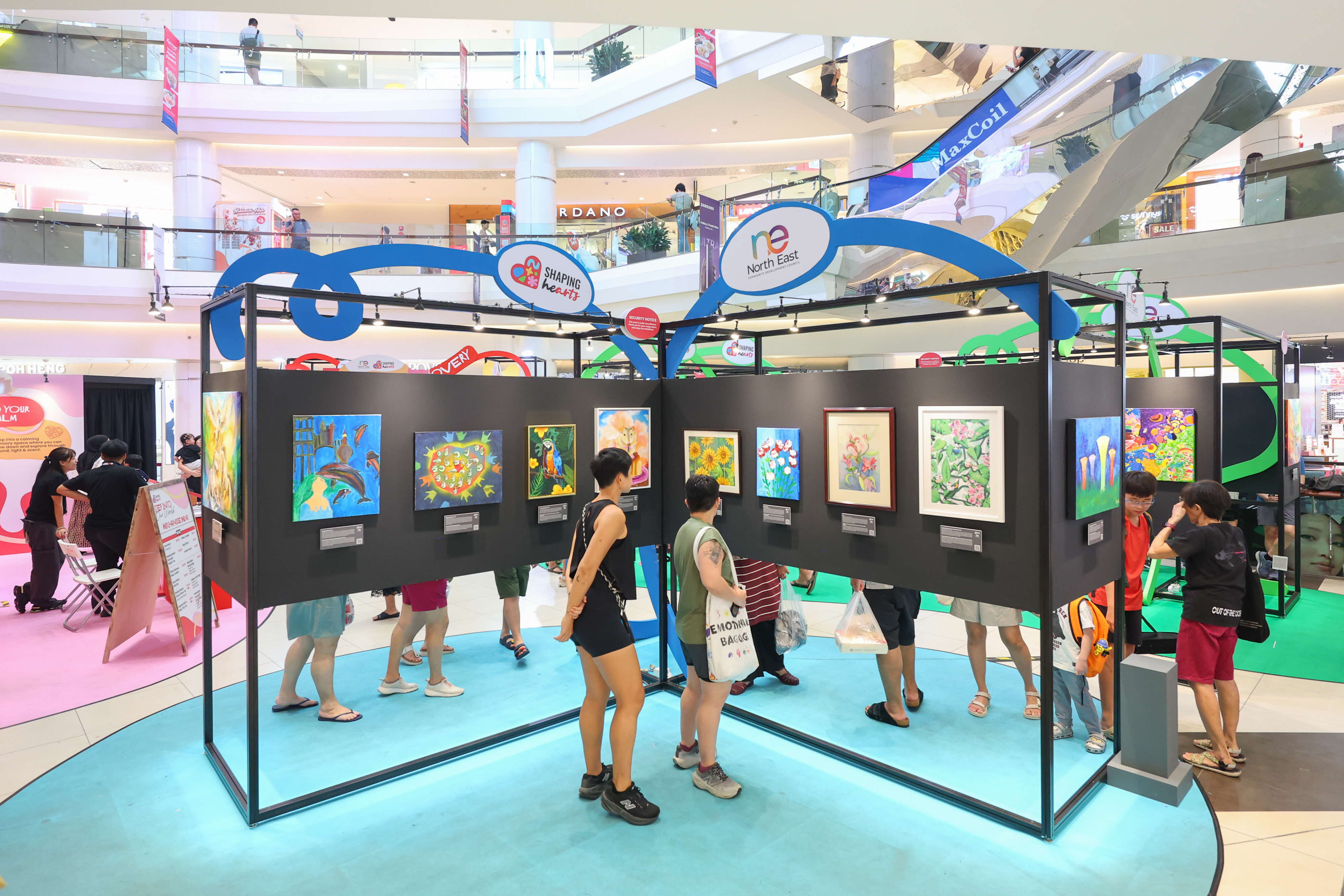 Residents viewing colourful artworks displayed across the Shaping Hearts exhibition at Tampines Mall.