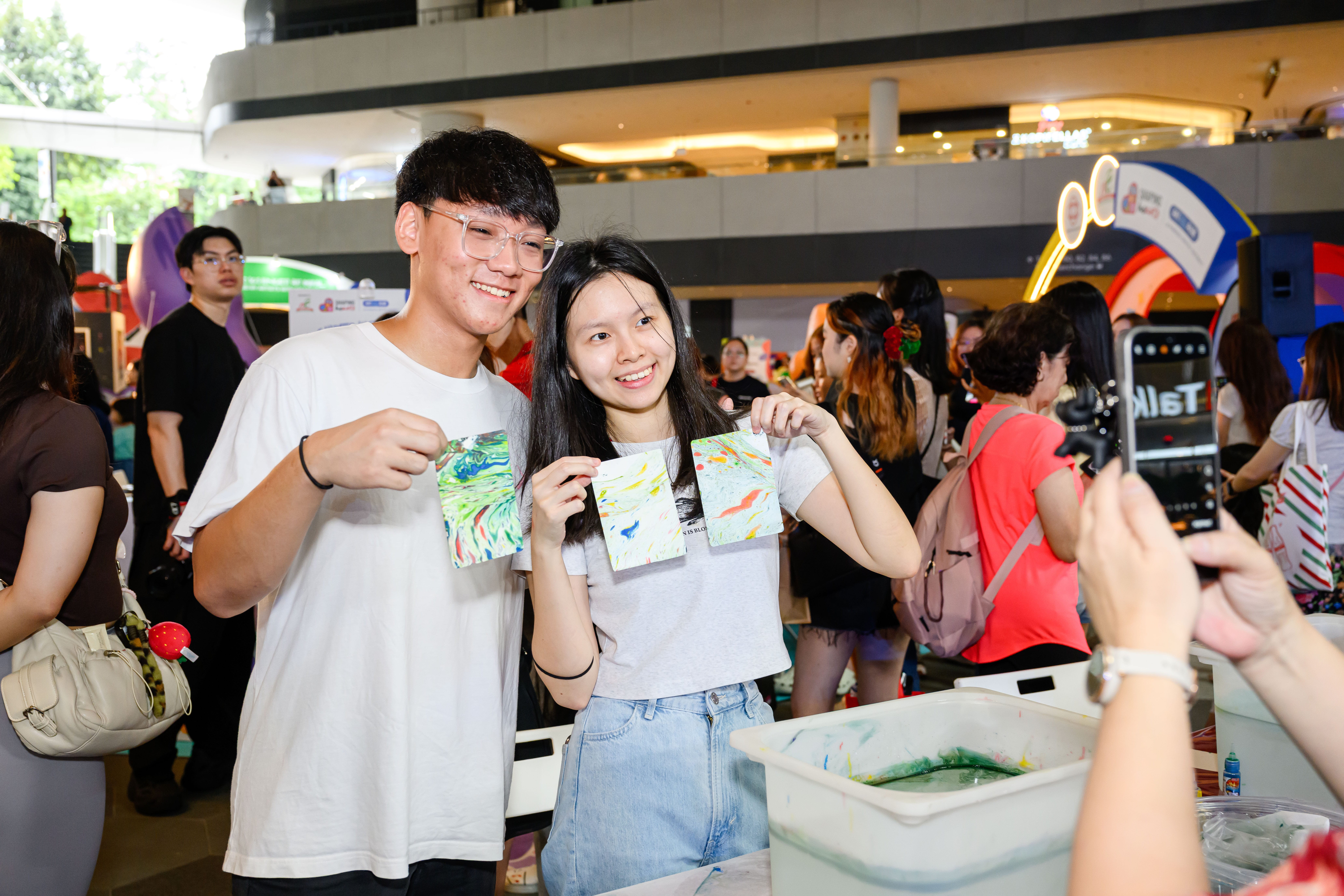 Couple smiling at the camera while holding their marble-dyed pouches.