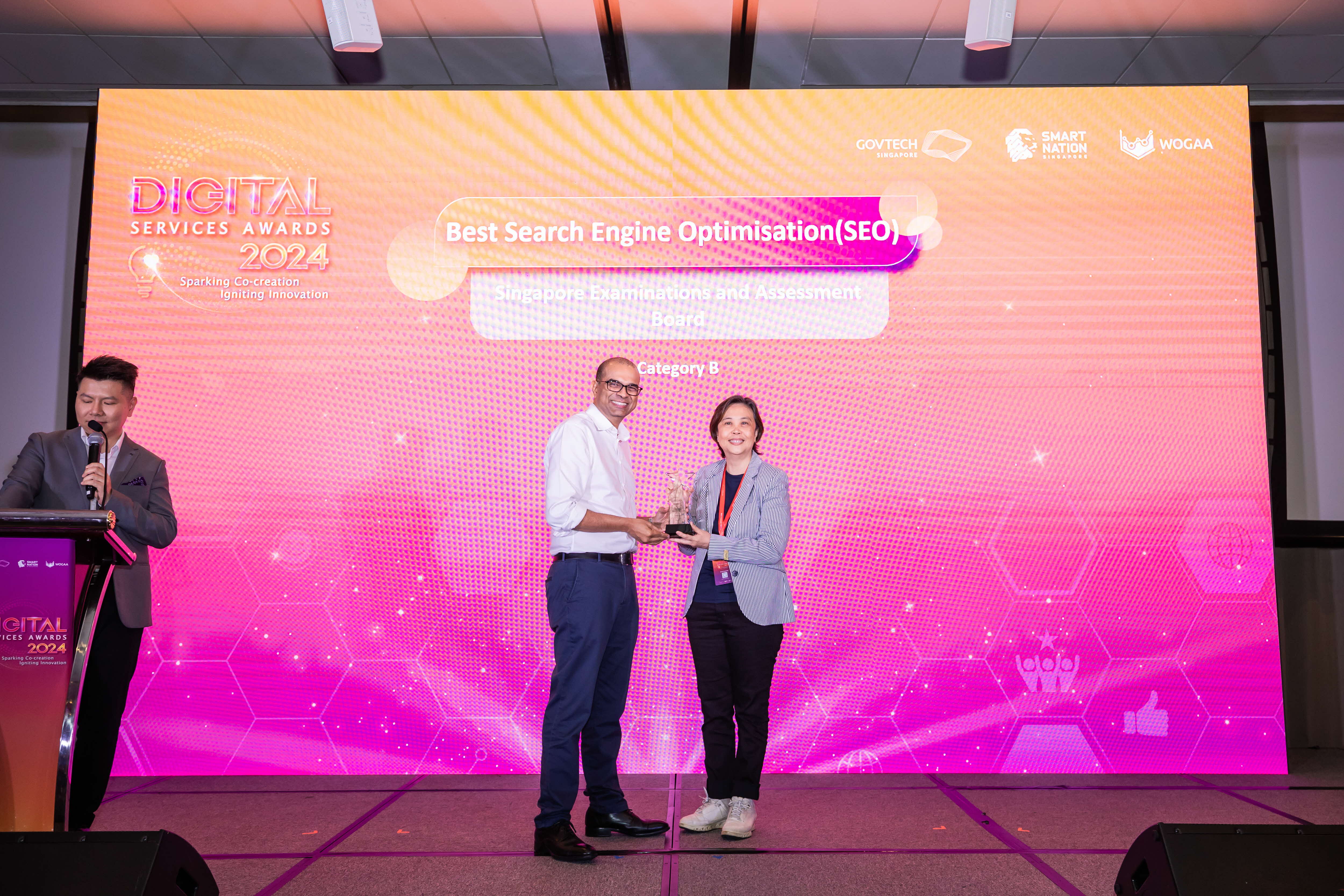 A person in a suit presents an award to another person on stage at the Digital Services Awards 2024 event.