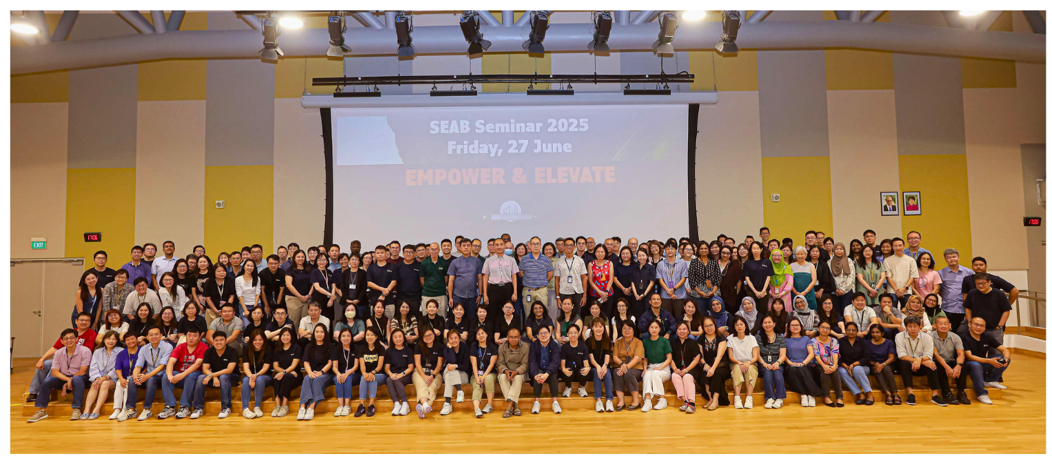 A large group of people gathered in front of a screen displaying "SEAB Seminar 2025, Friday, 27 June, Empower & Elevate".