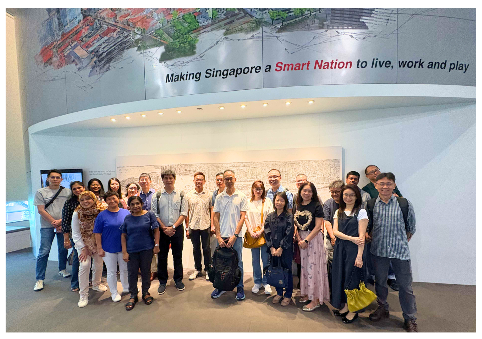 A group of people stands indoors under a sign that reads "Making Singapore a Smart Nation to live, work and play".