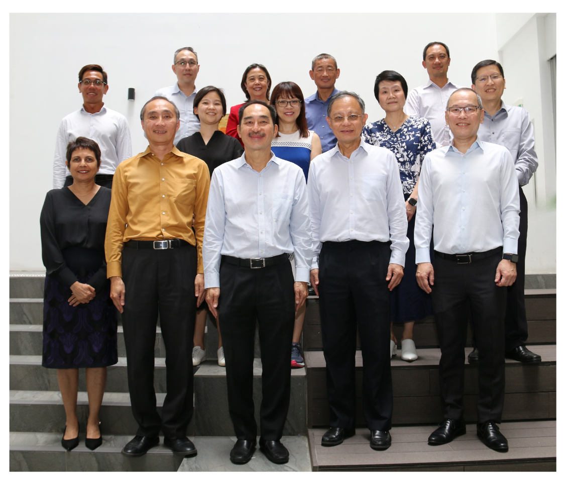 A group of people of various ages standing on stairs, dressed in business and casual attire.