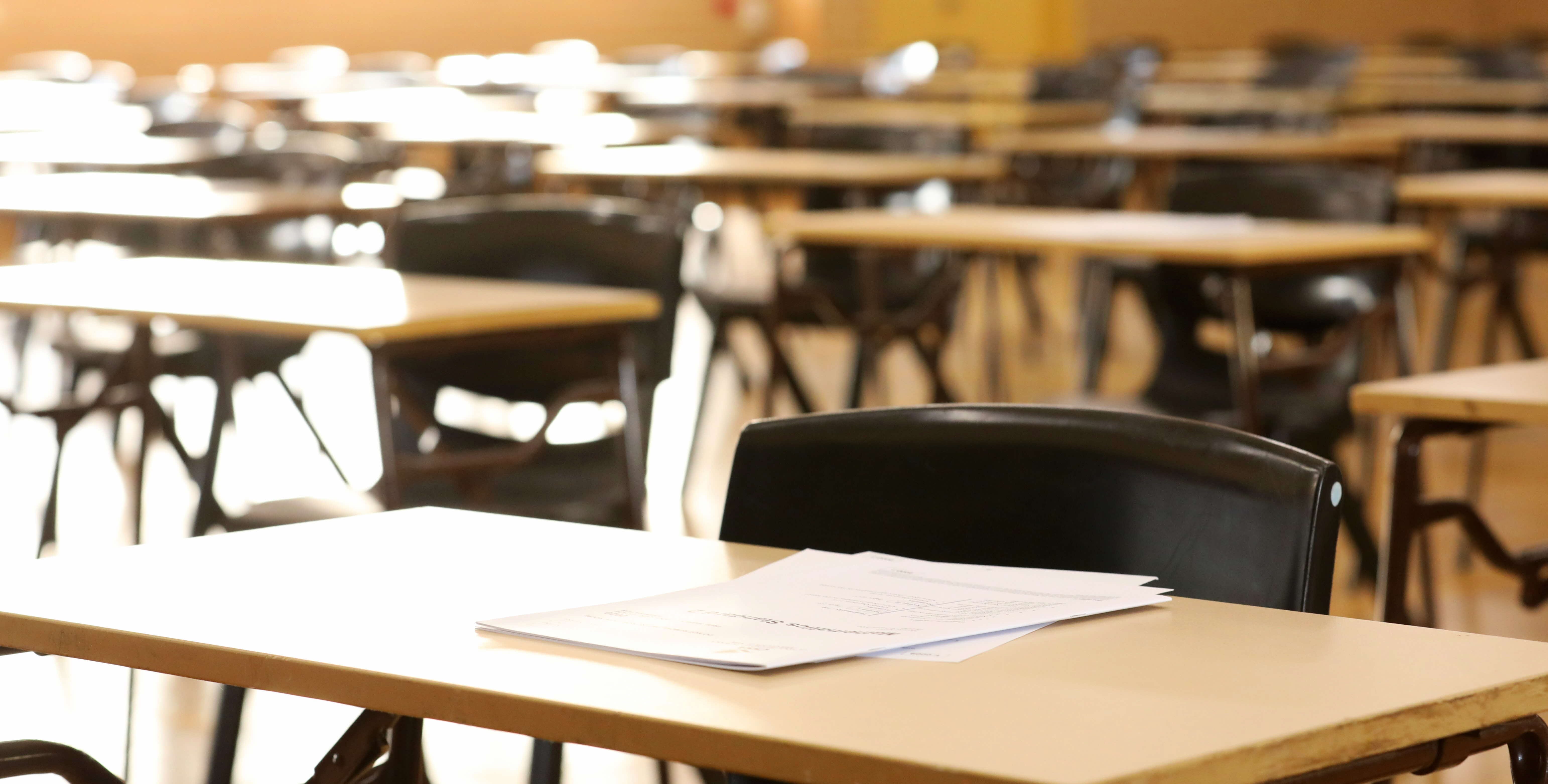 An empty classroom with papers on desk and links to Access Arrangements