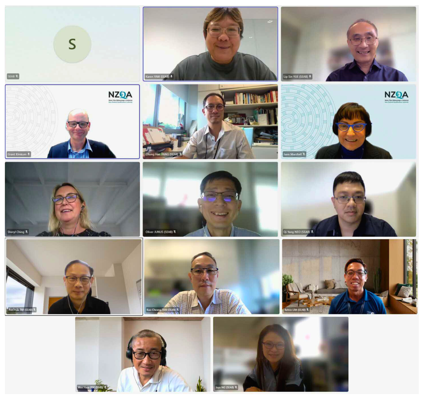 A virtual meeting grid displaying 14 participants and their backgrounds, including bookshelves, offices, and home settings.