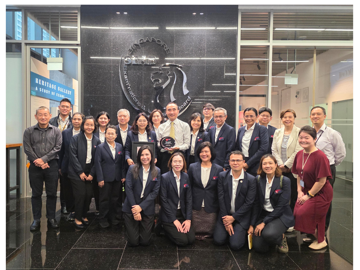 A group of people in business attire posing in front of the Singapore Examinations and Assessment Board sign.