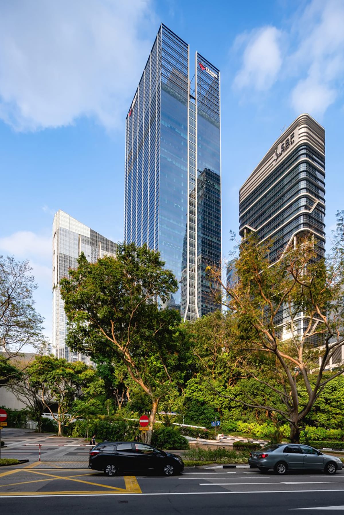 Tall glass skyscrapers with UOB and SBF logos, trees, and cars on the street.