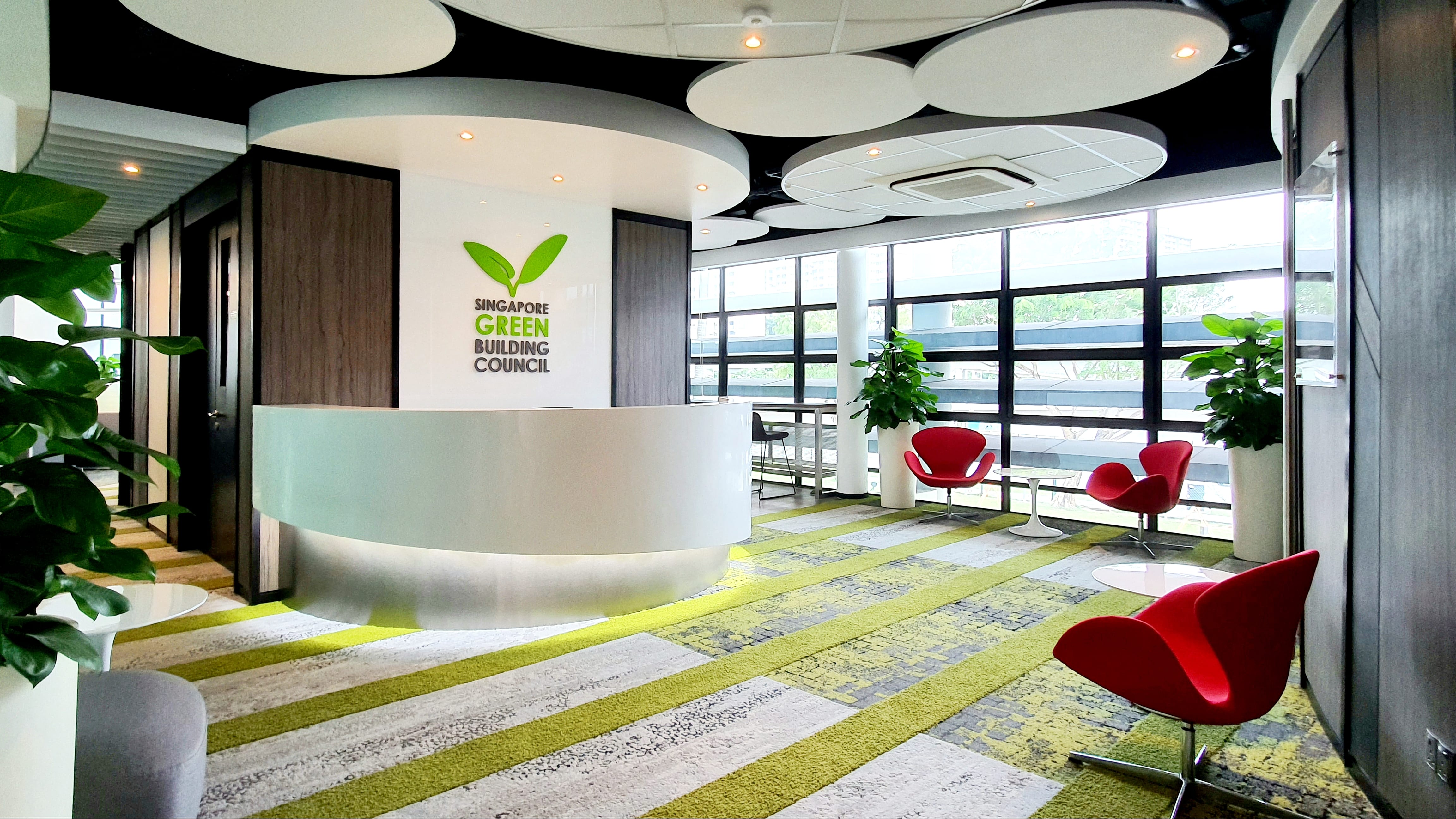 Singapore Green Building Council reception area, featuring a curved desk and red chairs.