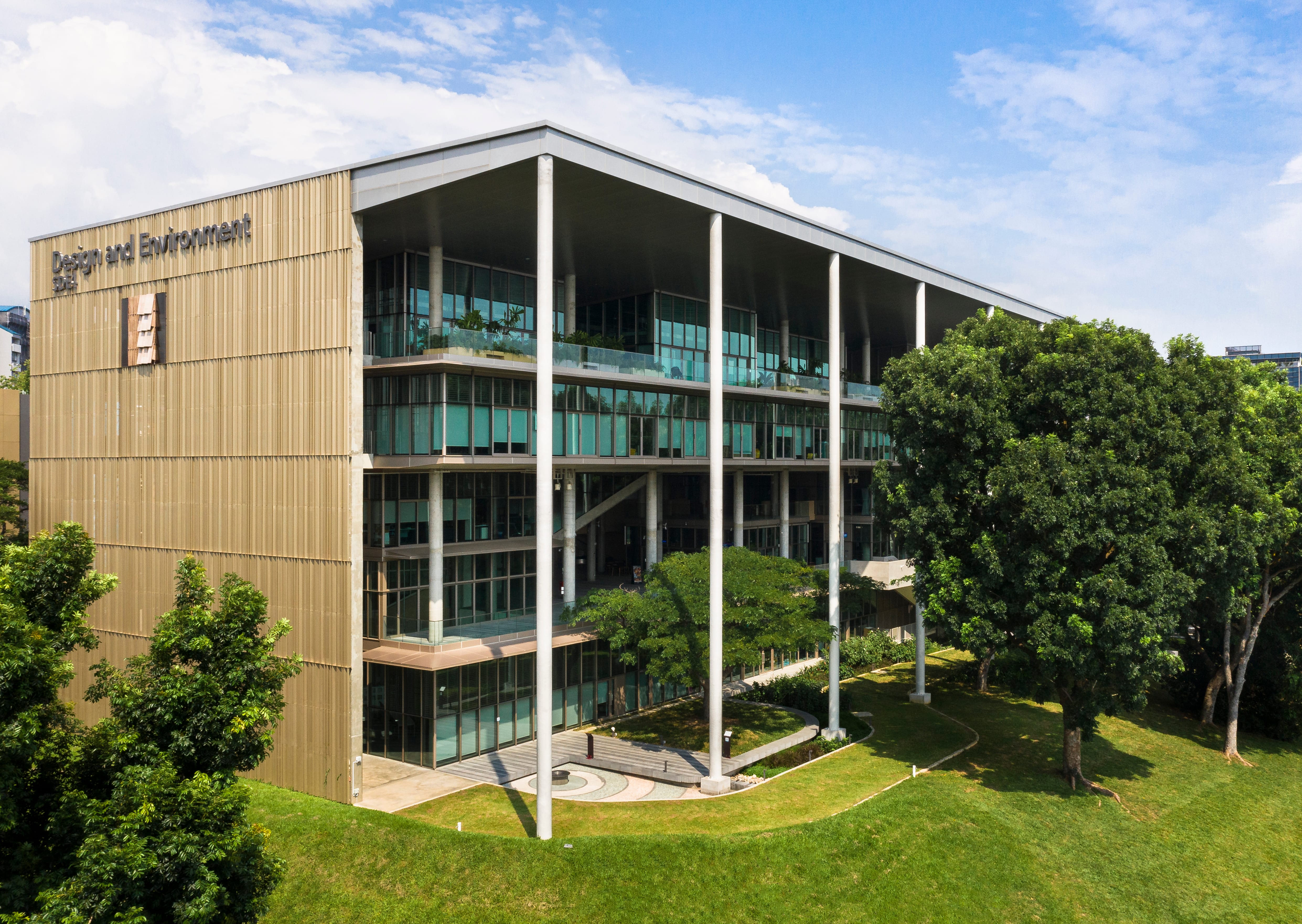 Modern Design and Environment building with silver columns on a green lawn.