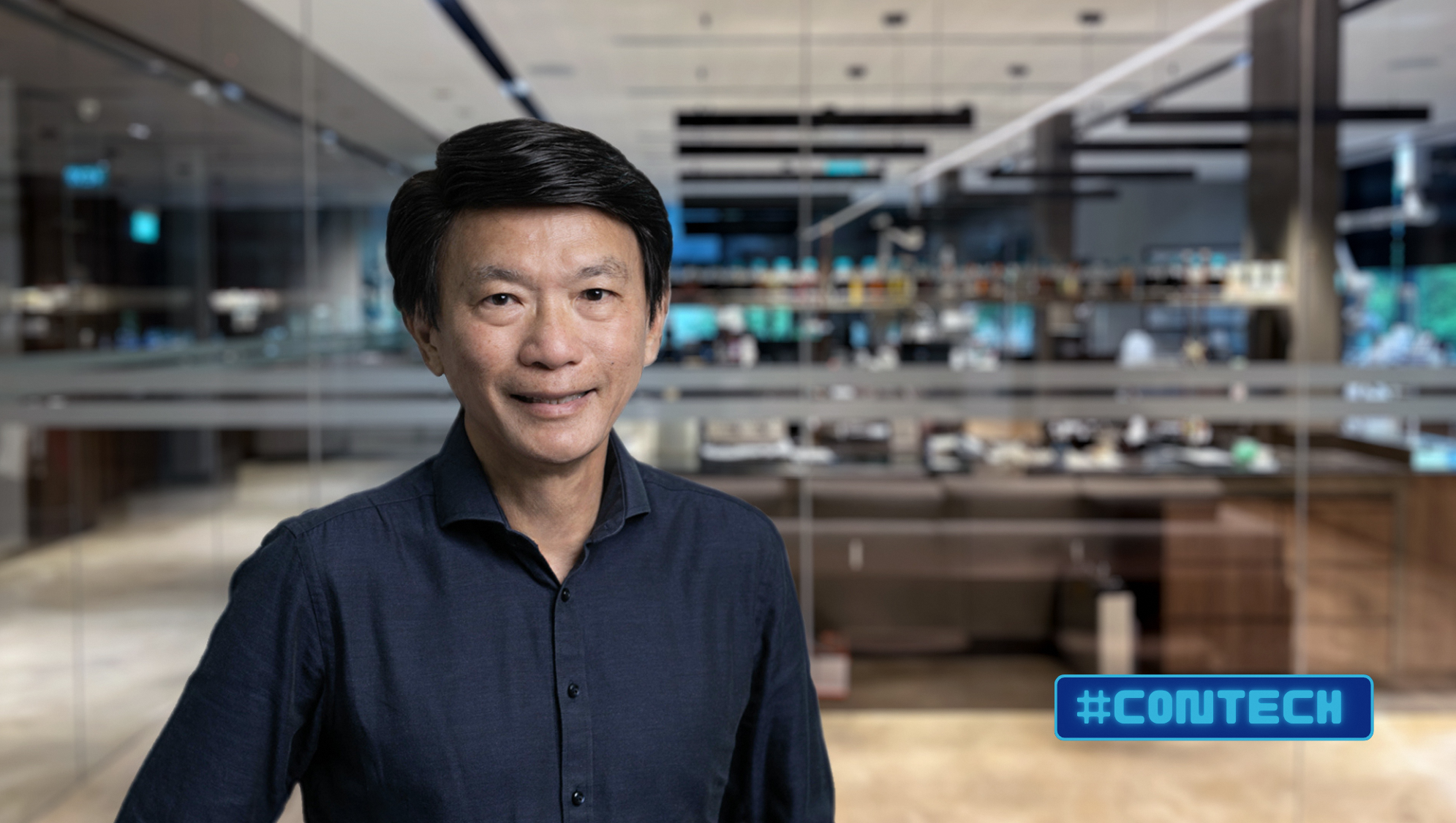 Asian man in dark shirt, blurred office backdrop with #CONTECH hashtag.