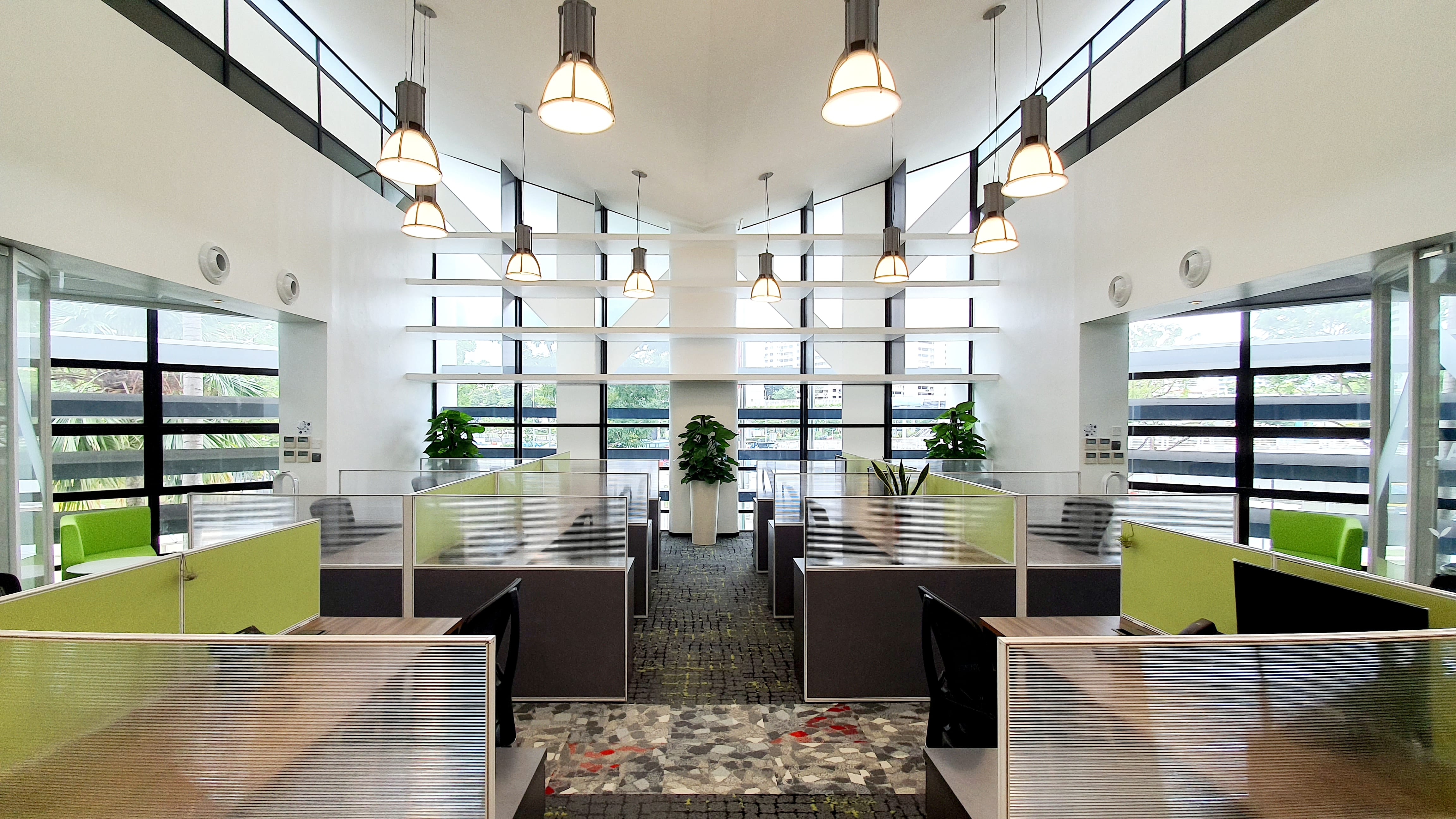 Open office with cubicles, pendant lights, and large windows.