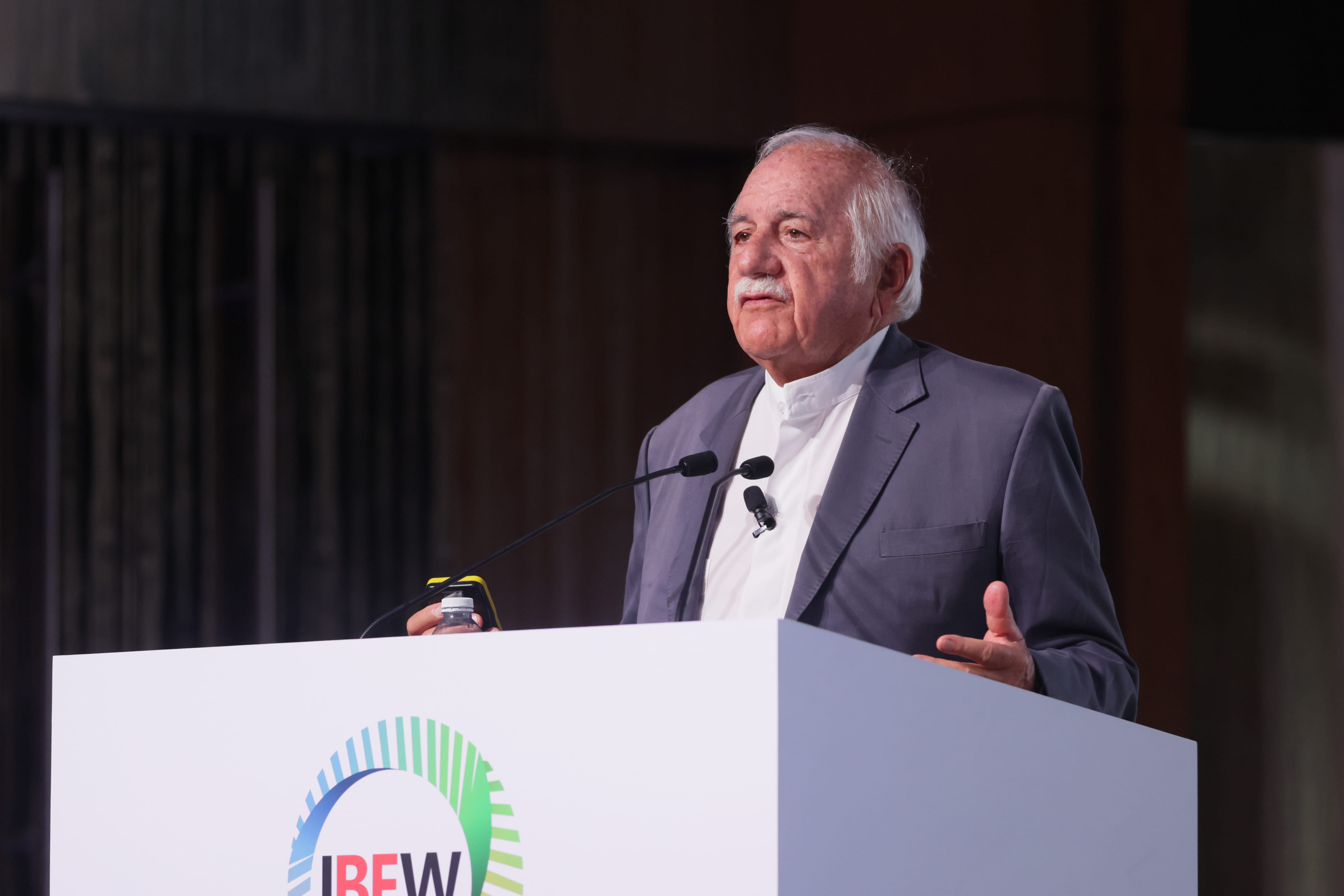 Man at IBEW podium speaks, holding a water bottle. He wears a gray suit.