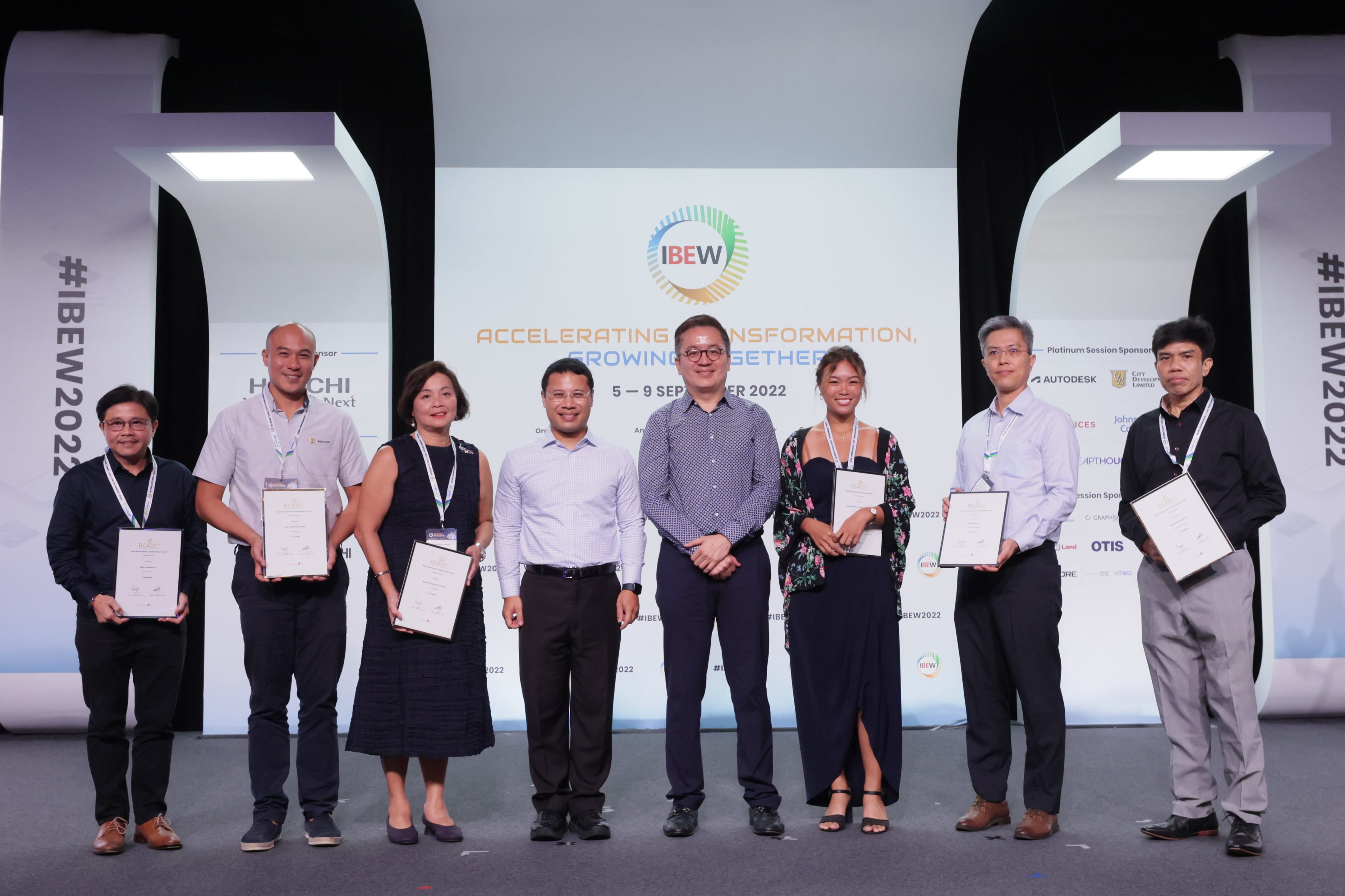 Seven people holding certificates on stage, IBEW logo backdrop and sponsor logos shown.