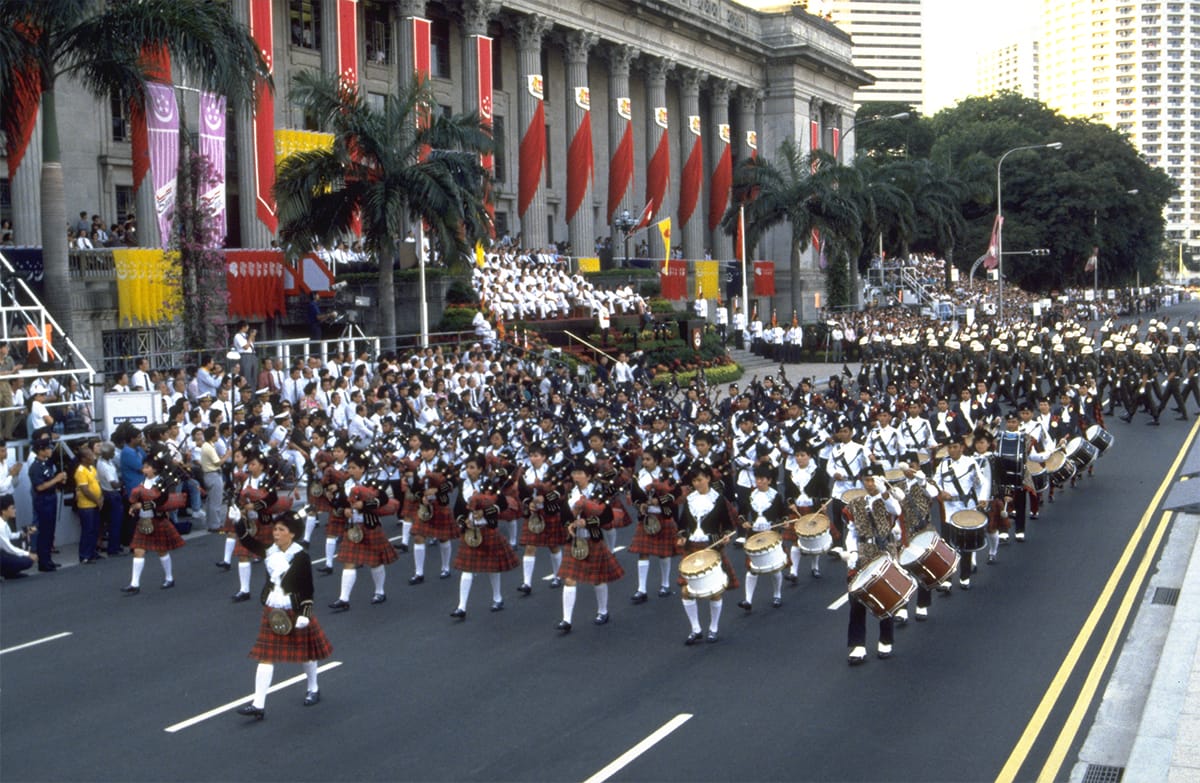 March-past by the combined bands of the Singapore Police Force and the Singapore Girl Pipers at the 1990 National Day Parade, held at the Padang. Ministry of Information and the Arts Collection, courtesy of the National Archives of Singapore (Media – Image No. 19980006518-0055).