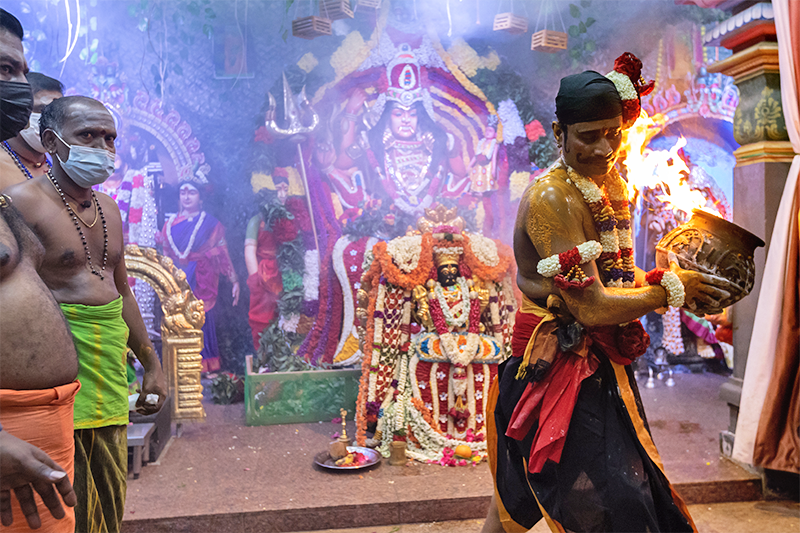 The pandaram (priest) carrying the agni kapparai (giant cauldron of fire). He is in the guise of Madurai Veeran, guardian of the goddess, at the Periyachi Amman shrine, Sri Mariamman Temple, 2021. Courtesy of the Hindu Endowments Board.