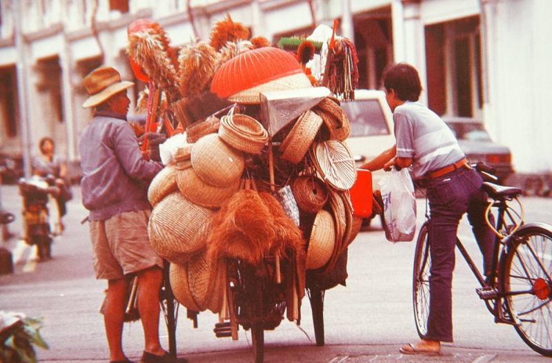Besides transporting various goods, cargo tricycle riders sometimes also sold things from their tricycle. Vendor selling household items from a tricycle, 1990s. Liesel Strauss Collection, National Library, Singapore.
