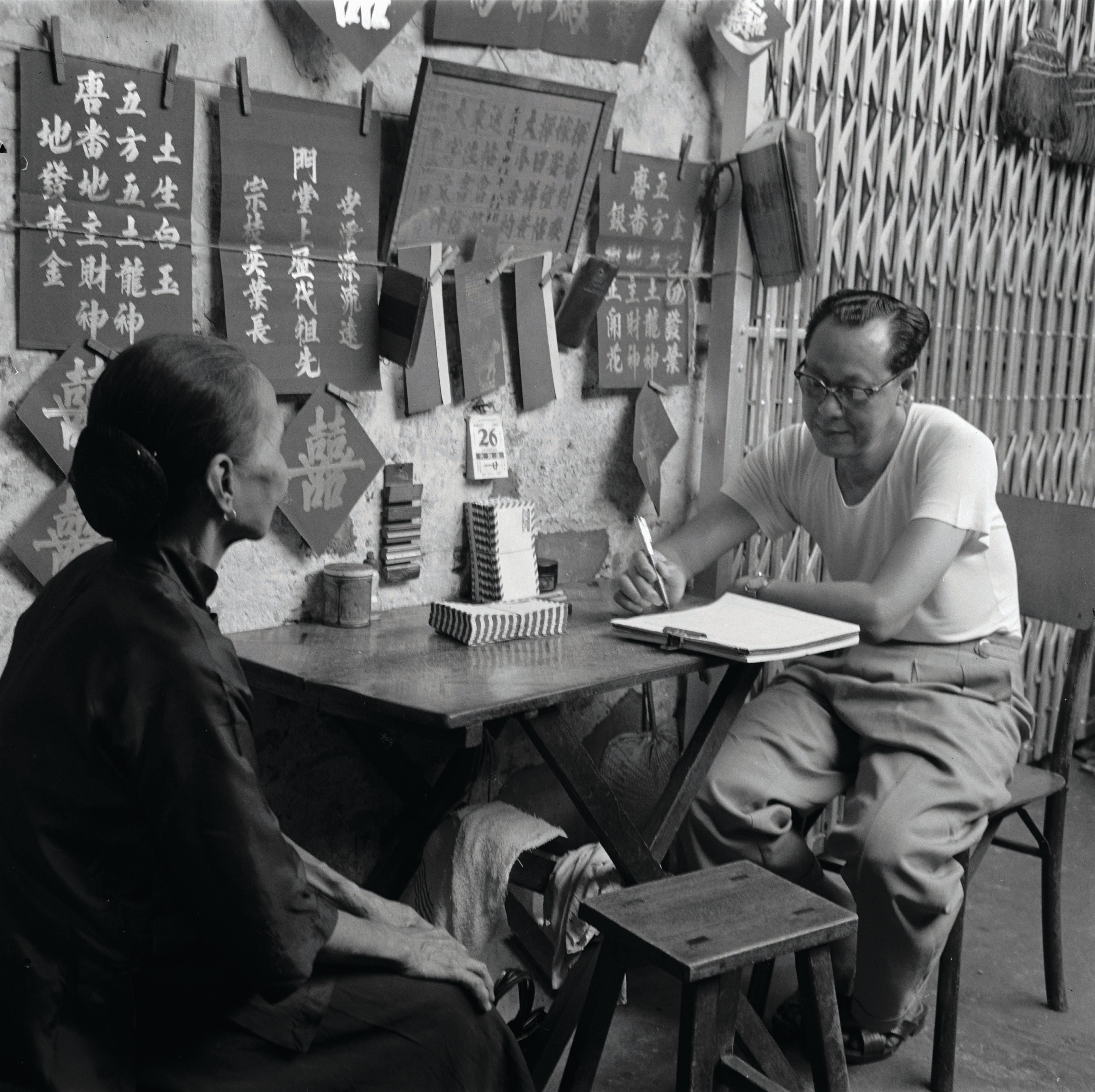 An elderly lady dictating her letter to a professional letter writer in Kreta Ayer, who set up his makeshift stall along a five-foot way, circa late 1970s. From the Kouo Shang-Wei Collection 郭尚慰收集. All rights reserved, Family of Kouo Shang-Wei and National Library Board Singapore 2007.