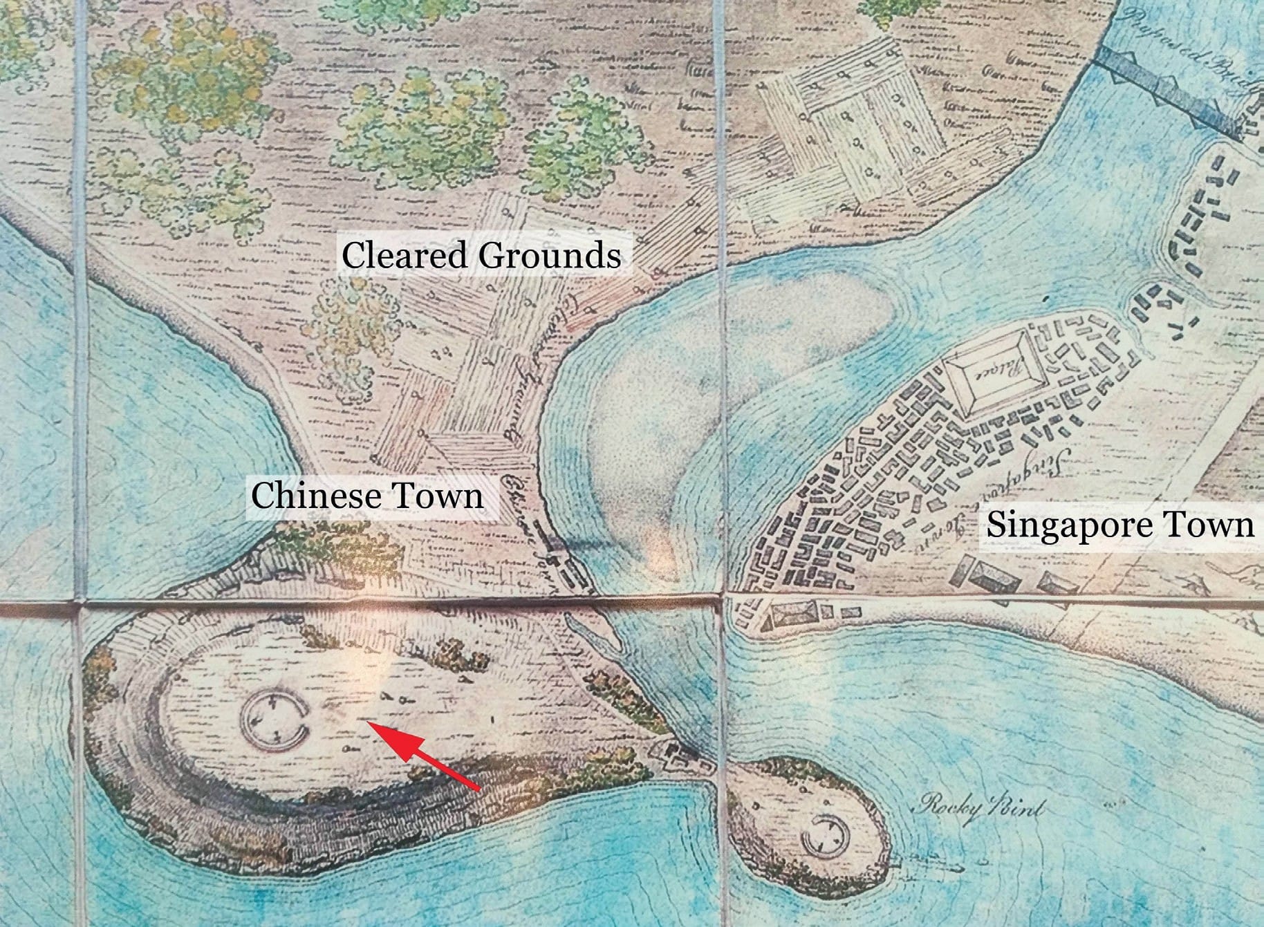 An old map shows labeled areas: Cleared Grounds, Chinese Town, Singapore Town, with a red arrow pointing to a specific location.