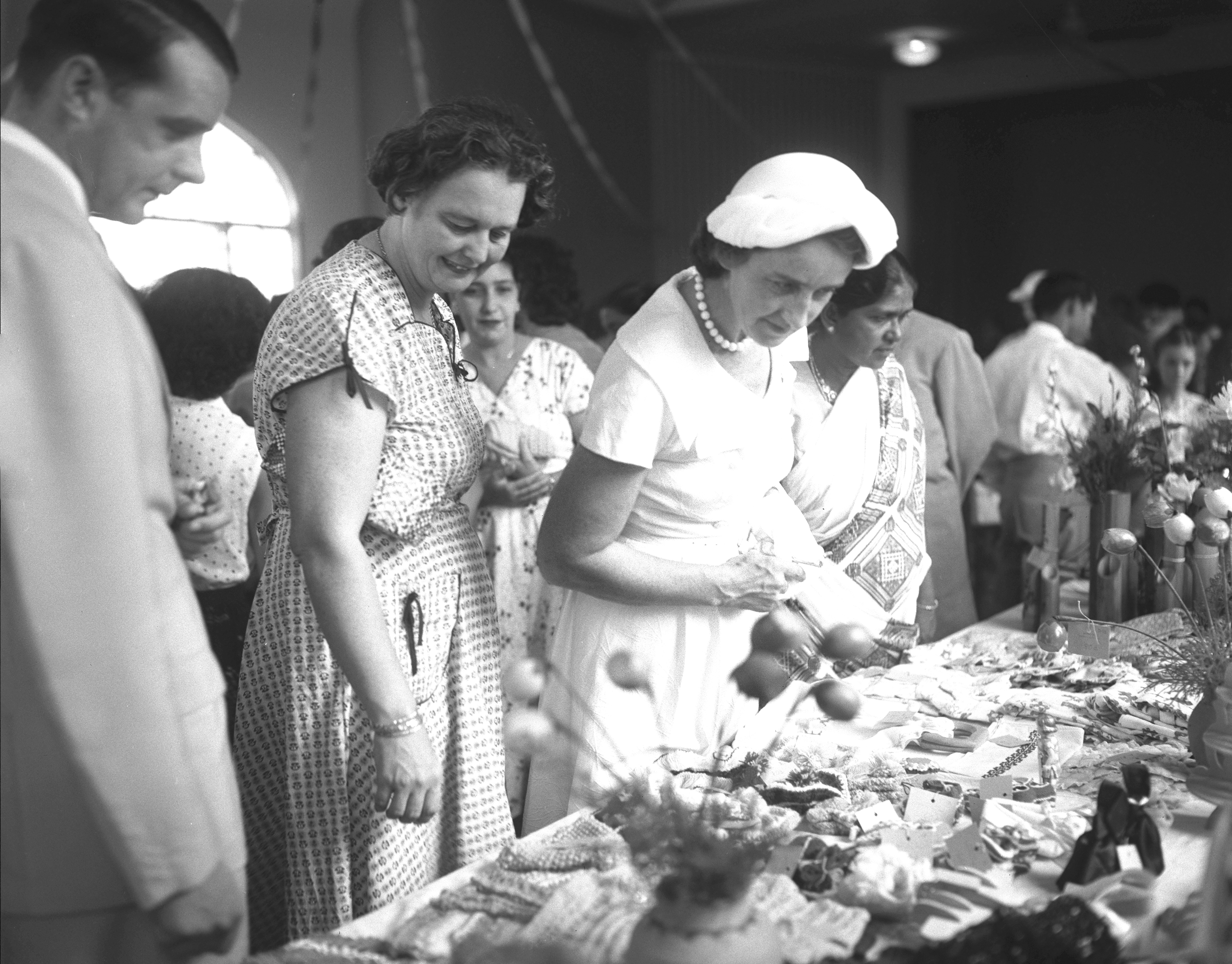 Lady Anne Black (wearing hat), wife of then Governor of Singapore Robert Black, at the annual sale of works organised by voluntary workers of the Children’s Social Centres, 1956. The items for sale were made by children at the centres. Ministry of Information and the Arts Collection, courtesy of National Archives of Singapore.