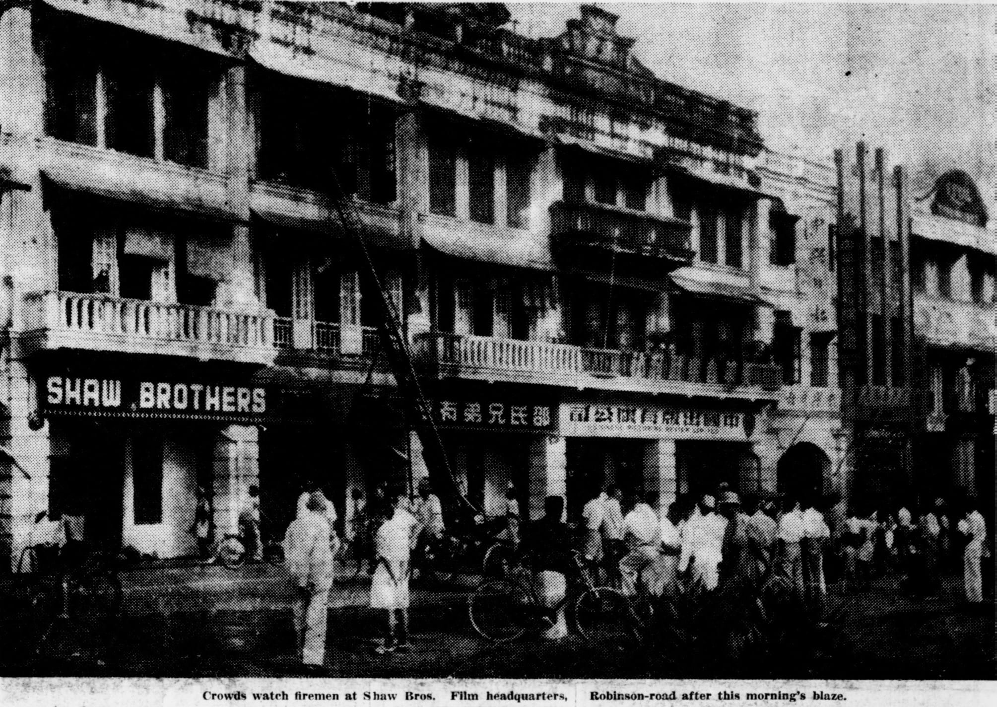 A crowd watches firemen on Robinson Road in front of the Shaw Brothers film headquarters after a morning blaze.