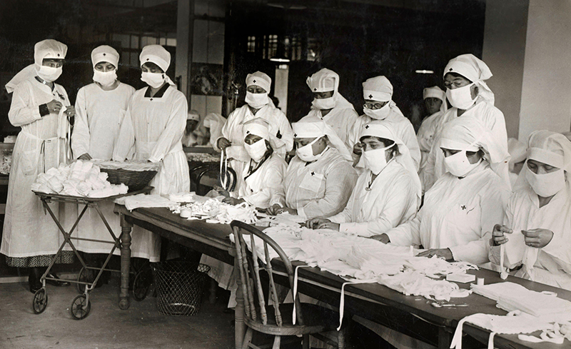 Red Cross volunteers making white gauze face masks, which became mandatory in many public situations in the United States during the 1918 influenza pandemic. Mask-wearing was, however, not mandatory in Singapore at the time. From Shawshots/Alamy.