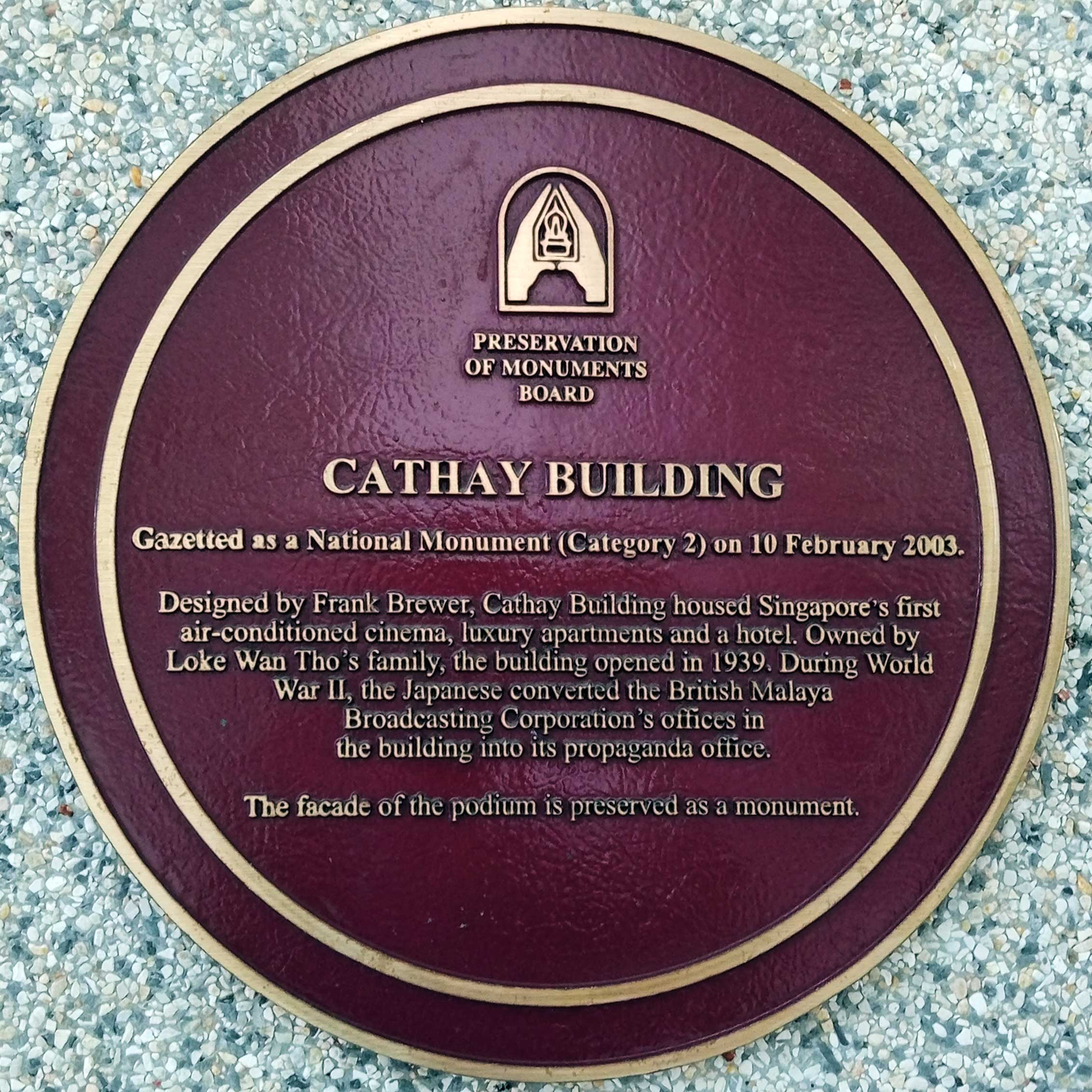 A maroon plaque with gold text describes the Cathay Building as a national monument, opened in 1939, designed by Frank Brewer.