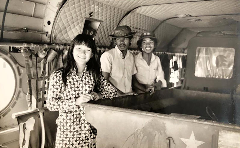 Three people stand inside a vintage military aircraft with visible equipment and a quilted ceiling.