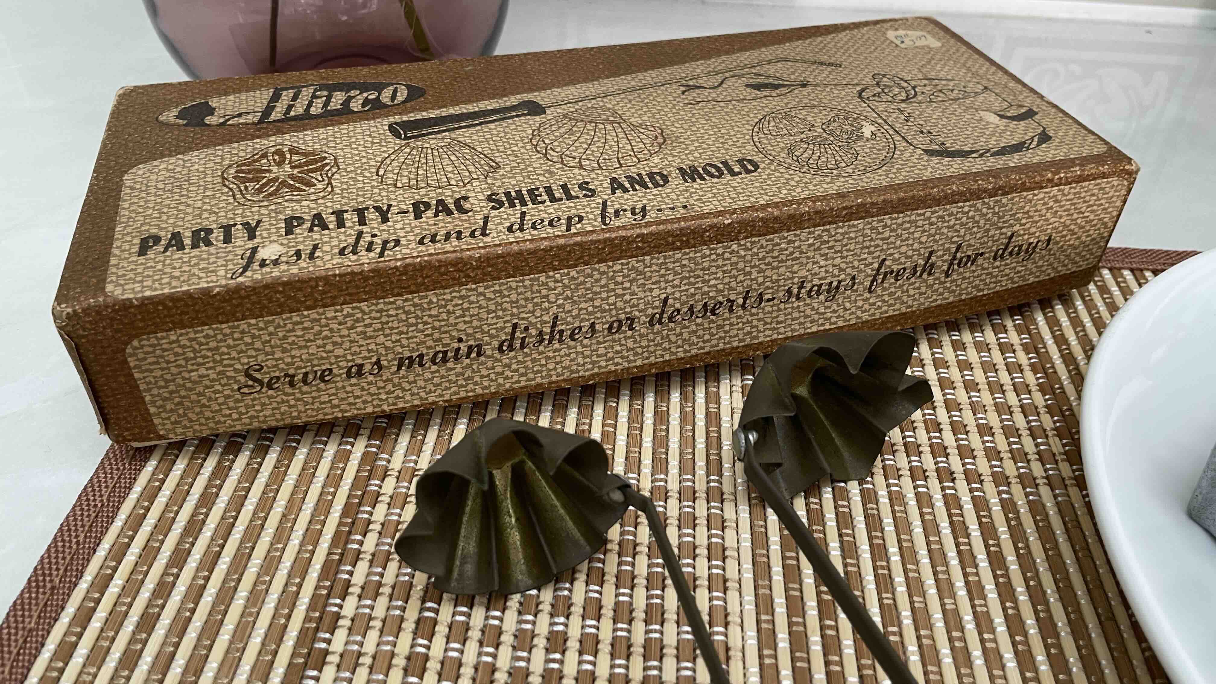 Vintage box labeled "Party Patty Pac Shells and Mold" with two metal molds on a woven mat.