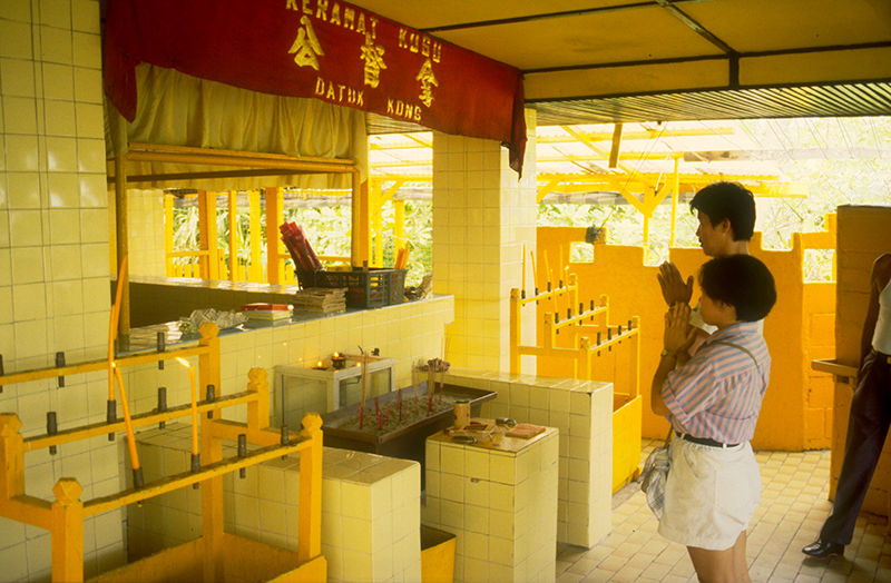 A Chinese couple at the shrine of Dato Syed Abdul Rahman, 1990. They are standing at the same spot as the group in the c. 1930 photograph above. Ministry of Information and the Arts Collection, courtesy of National Archives of Singapore.