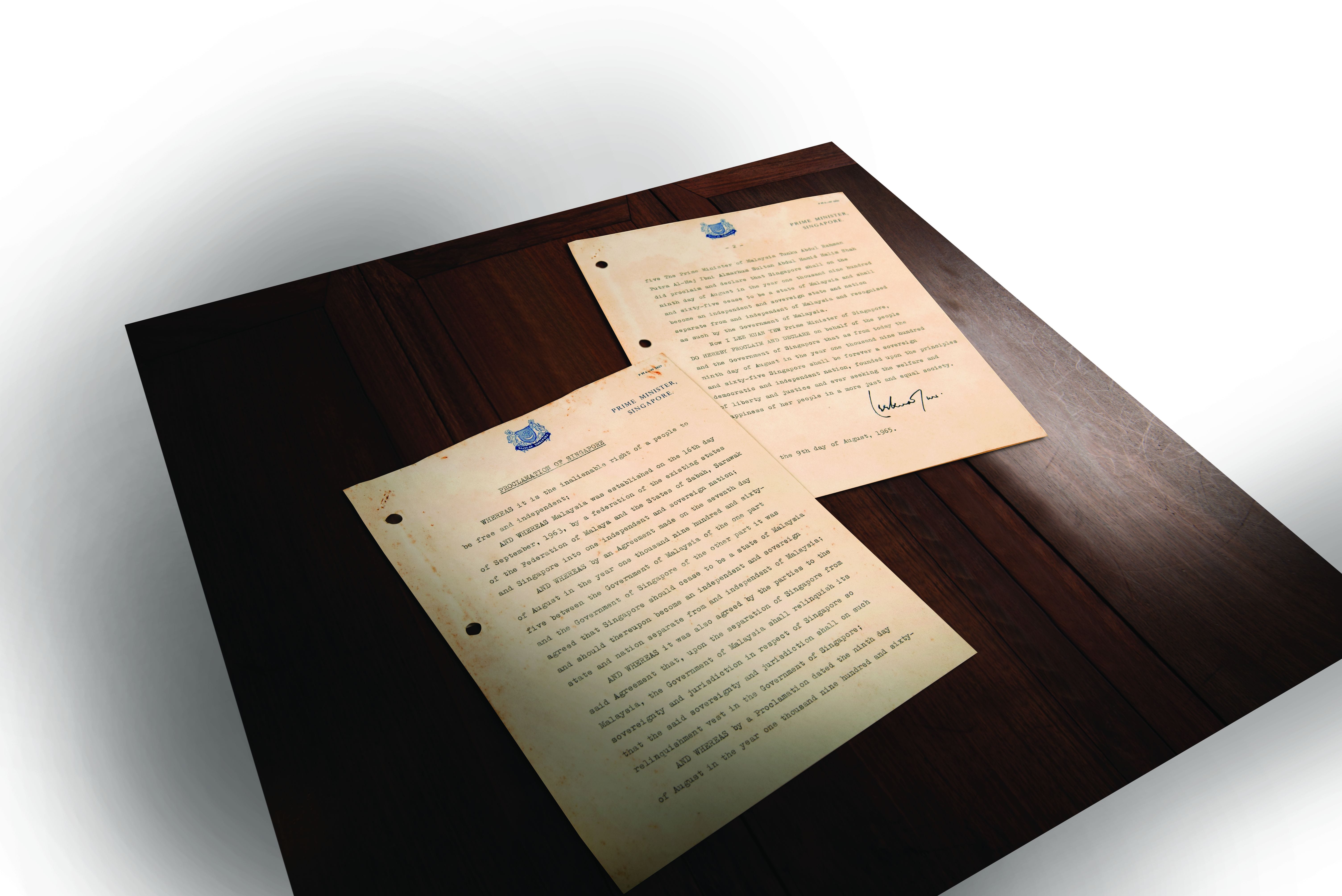 Two aged documents with typed text and blue emblems are displayed on a wooden surface; one is signed.