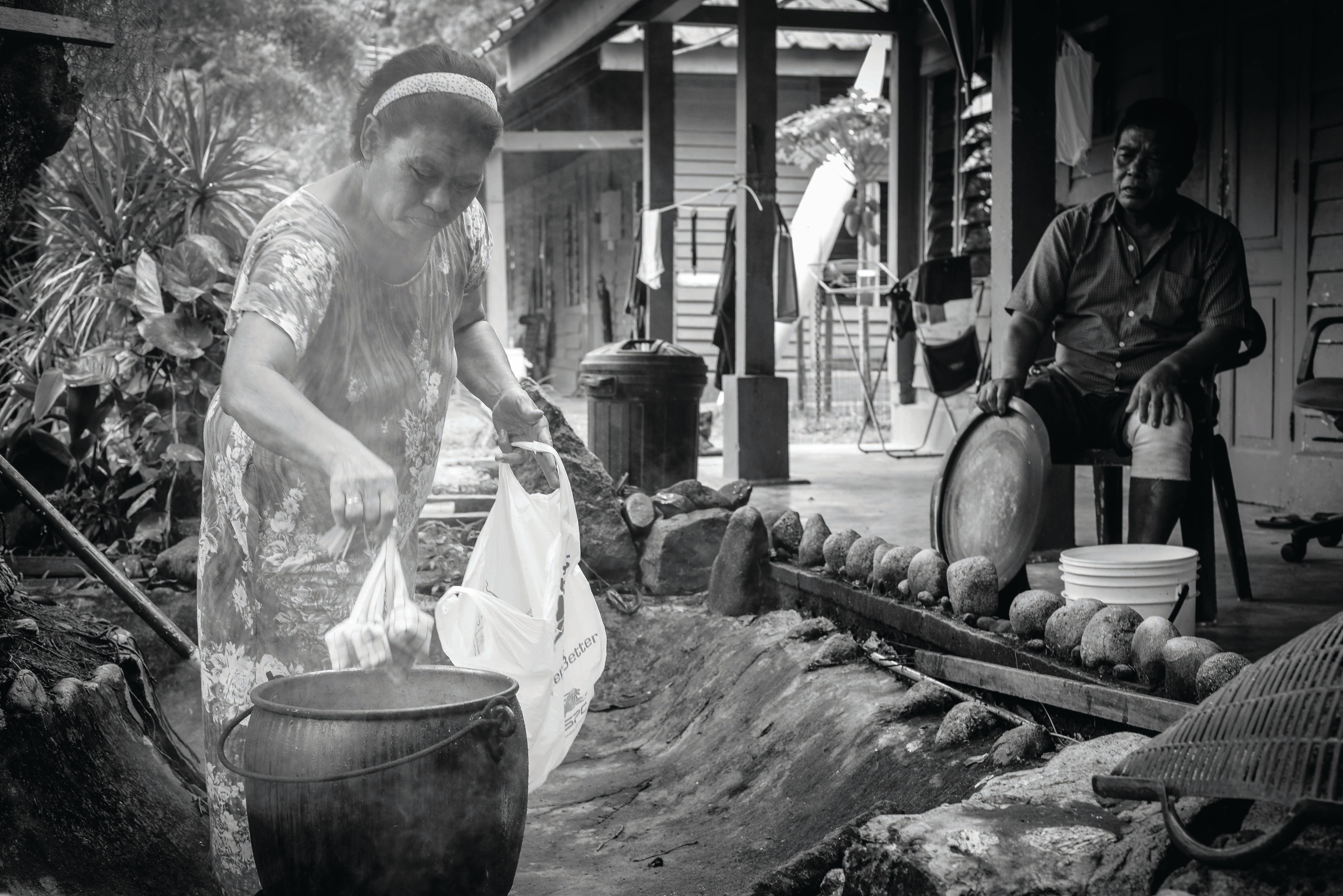 On St John's Island, Mohamed Sulih Bin Supian – born and bred on the island – and his wife Fuziyah use the space in front of their home to cook rice dumplings known as ketupat in preparation for Hari Raya Aidilfitri. He has special permission to live on the island. Photo by Edwin Koo.