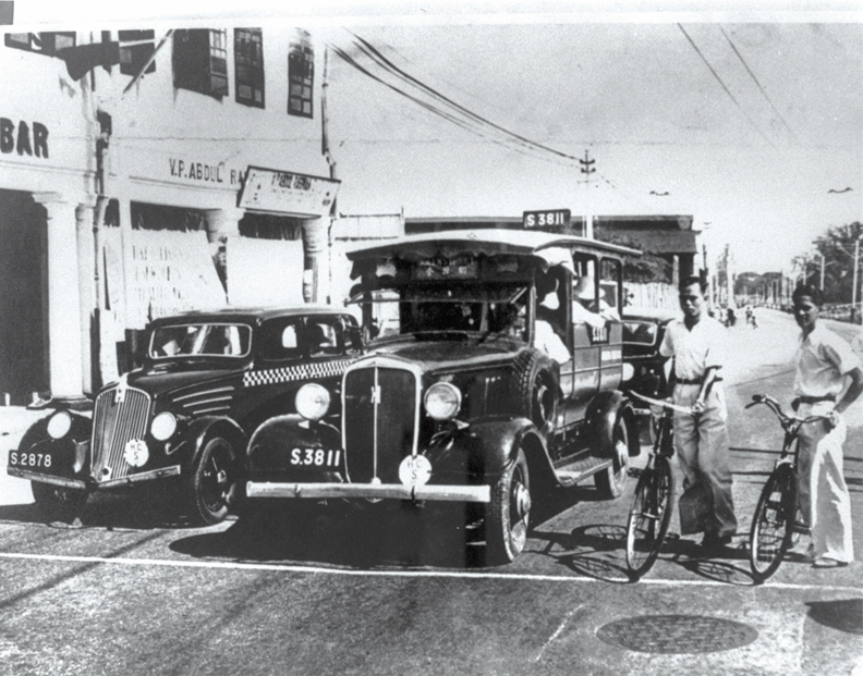 A mosquito bus in between a taxi and a cyclist, 1935. F W York Collection, courtesy of National Archives of Singapore.