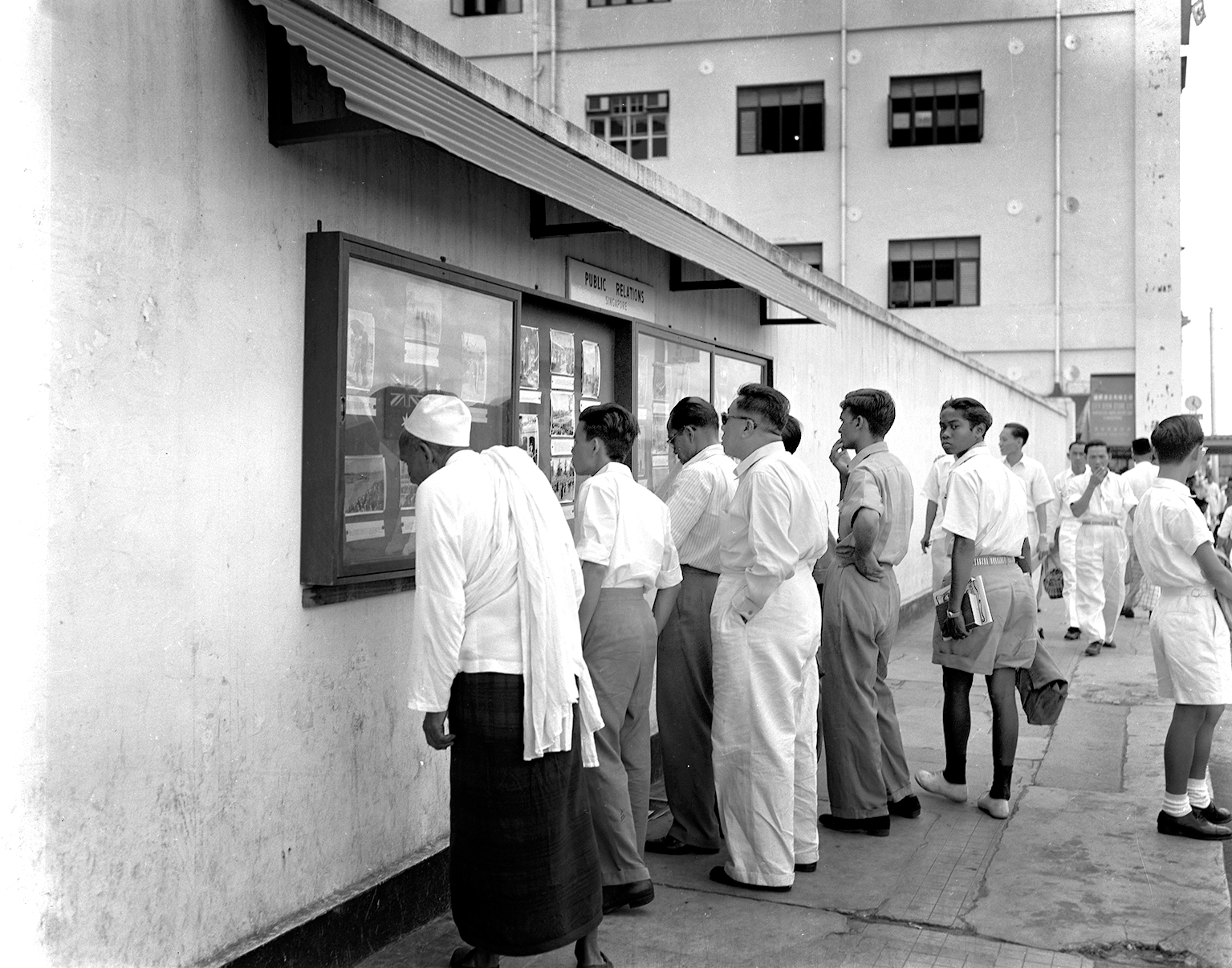 Photo boxes containing images and notices were used to disseminate information to the public. This photo was taken at Collyer Quay, 1954. Ministry of Information and the Arts Collection, courtesy of National Archives of Singapore.