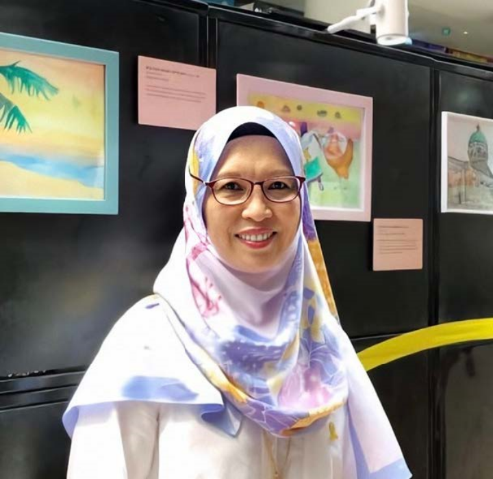 Person with glasses and a floral hijab in front of framed art.