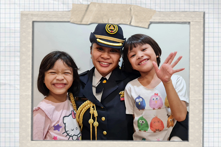 Woman in uniform poses with two smiling children in a framed photo.