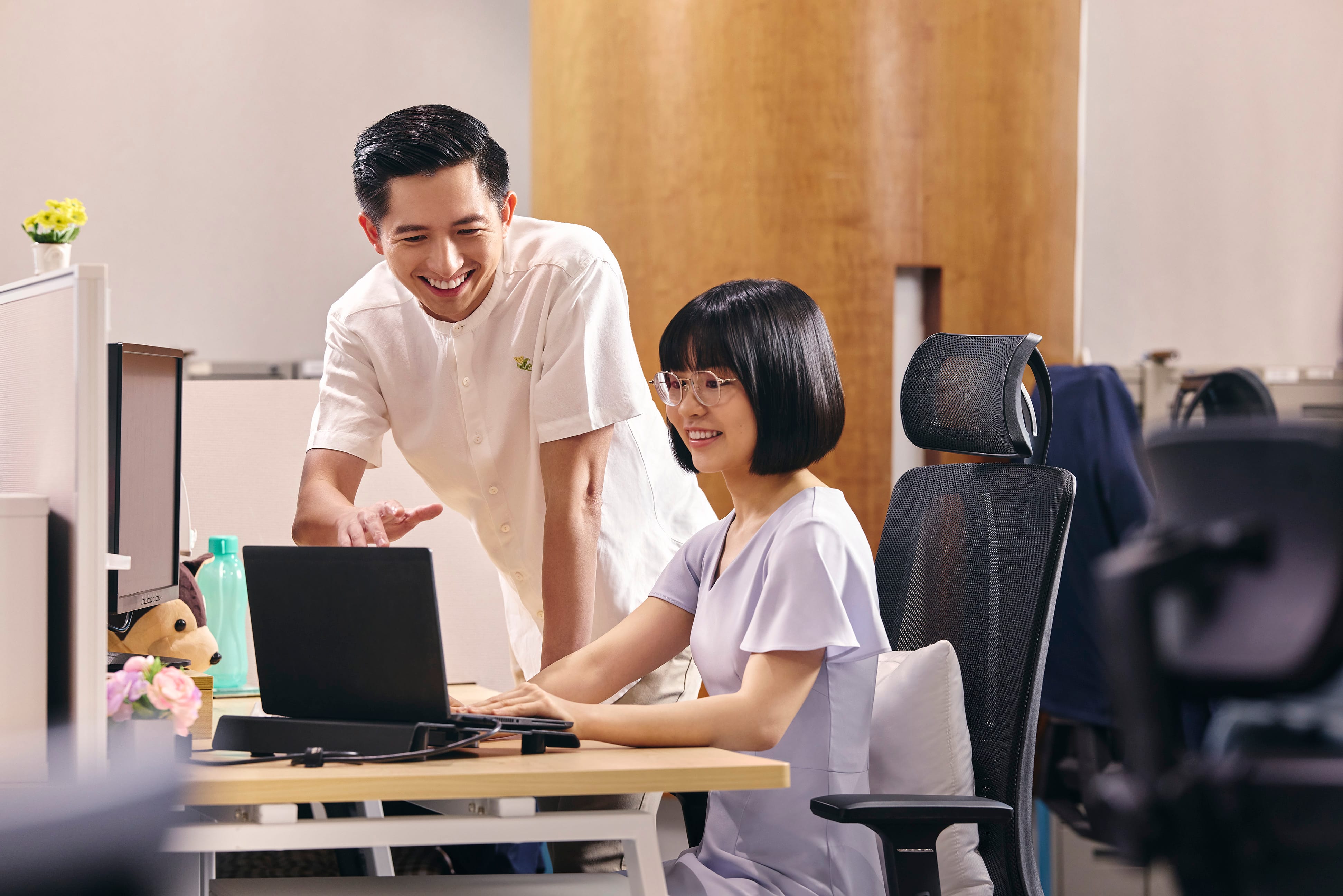 Two people gathered around a computer under blue lighting, discussing or working on a project.
