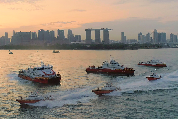 Fireboats speed on water; Singapore skyline with Marina Bay Sands in background.