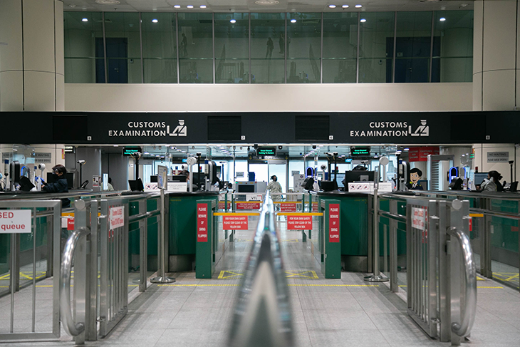 Customs examination area featuring metal queue gates and staffed desks.