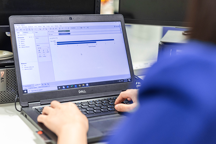 Person typing on a Dell laptop, a bar chart is visible on the screen.