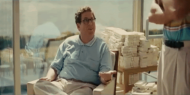 Jonah Hill as Donnie Azoff sits near stacks of money talking to a man in swim trunks.