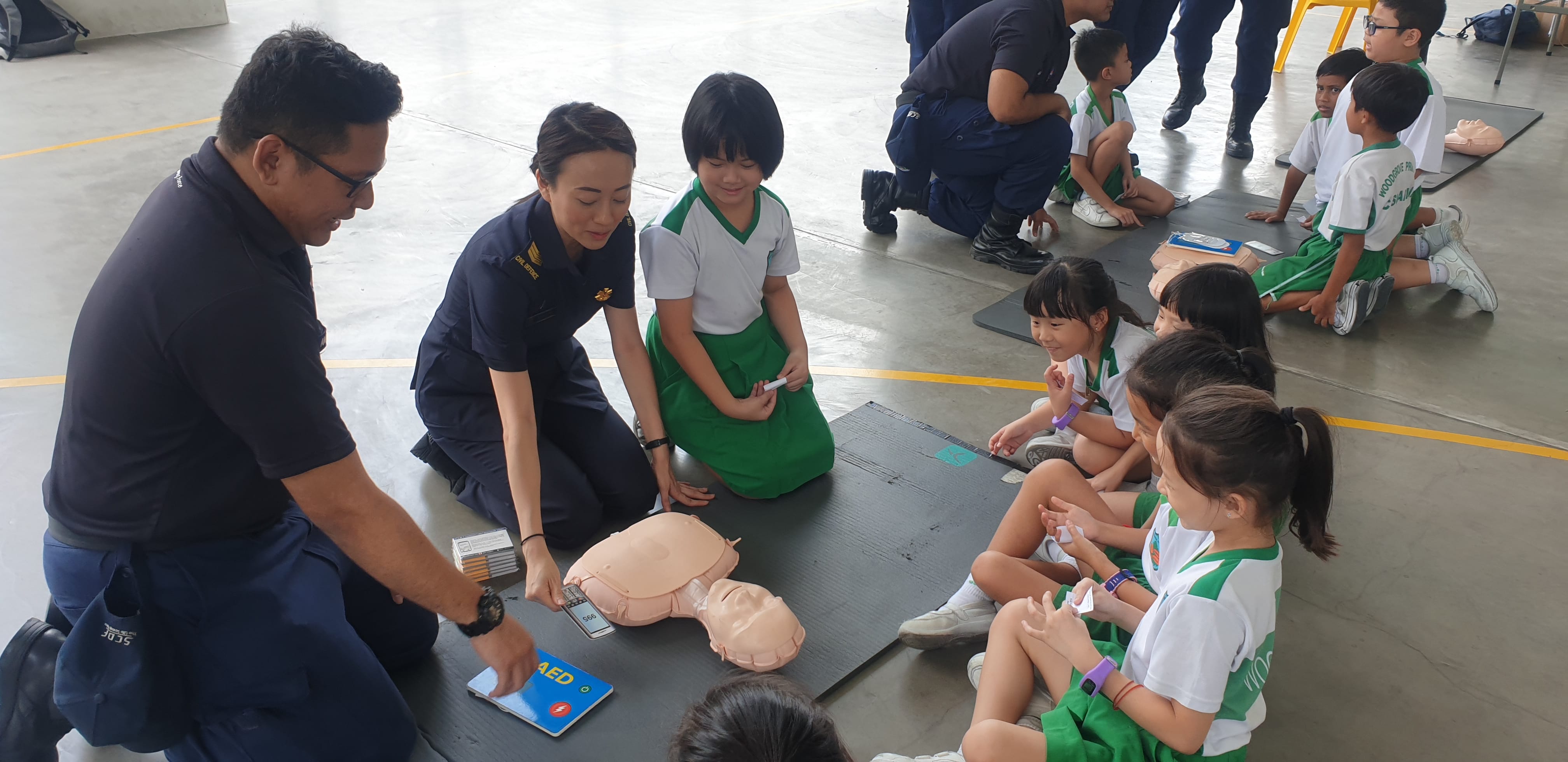 Uniformed officers conducting a safety awareness briefing for students gathered around an information board.