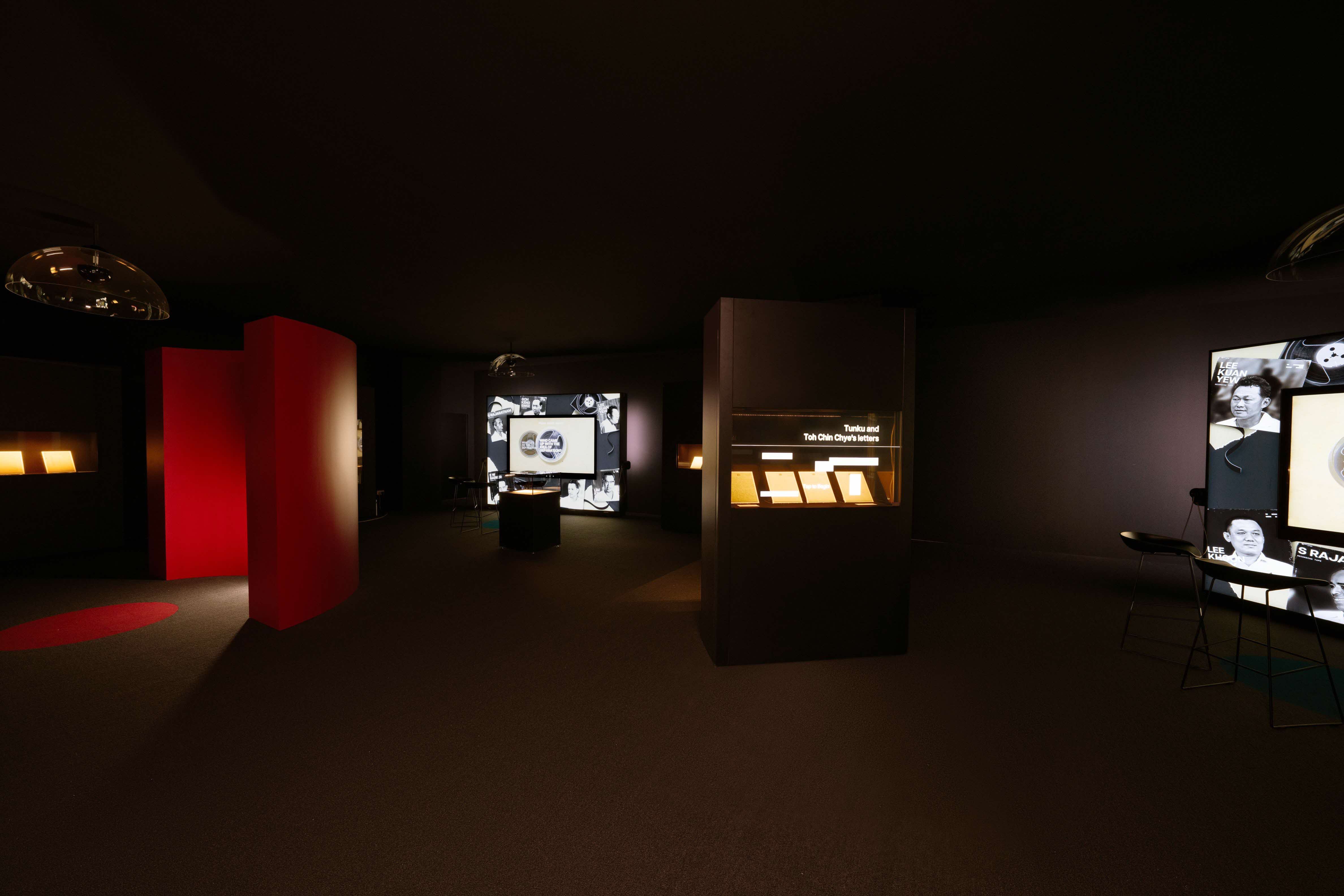 The room features illuminated display panels, a red wall segment, and exhibits with text and images.