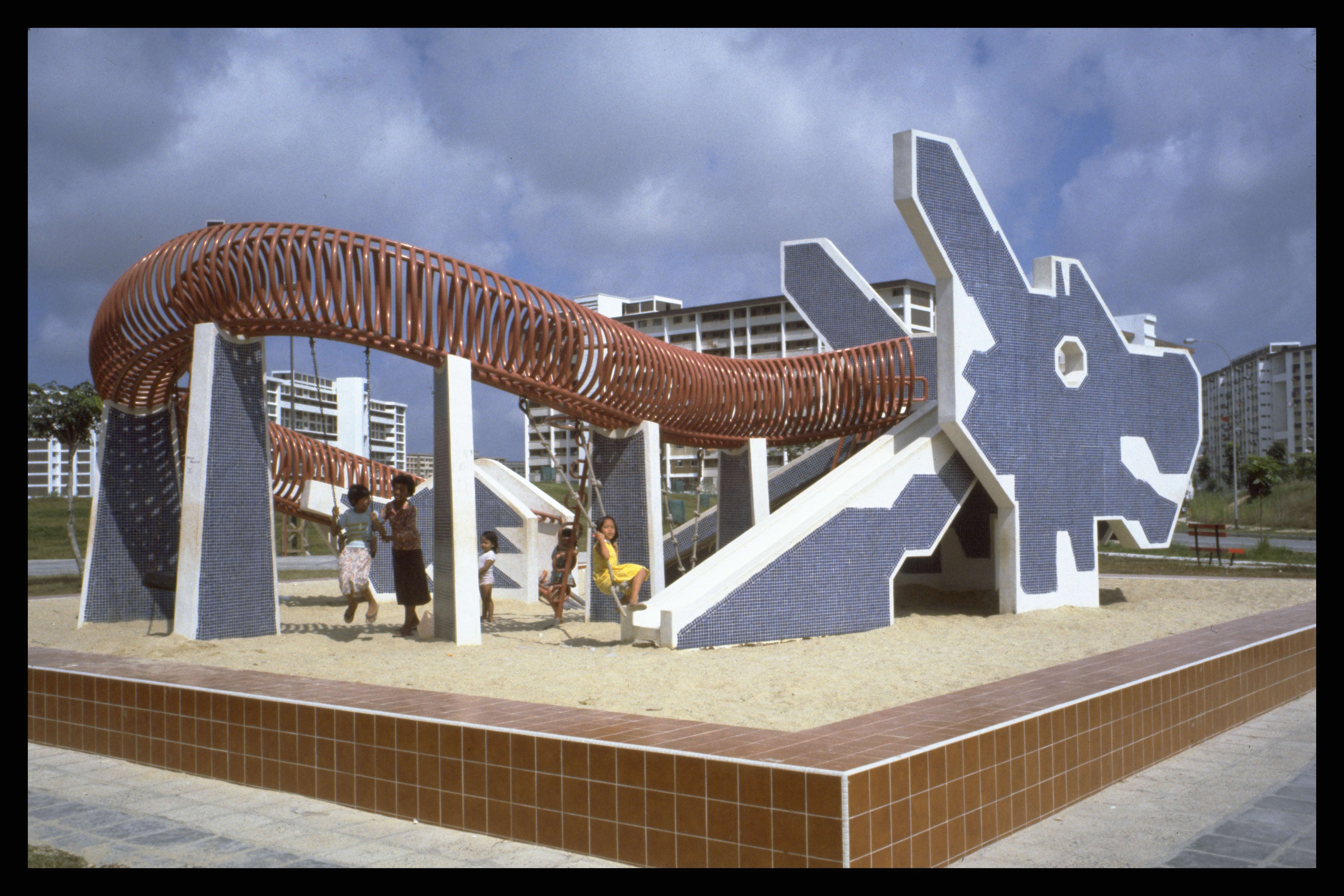 Children playing at a playground with a large, dragon-shaped structure featuring slides and tunnels.