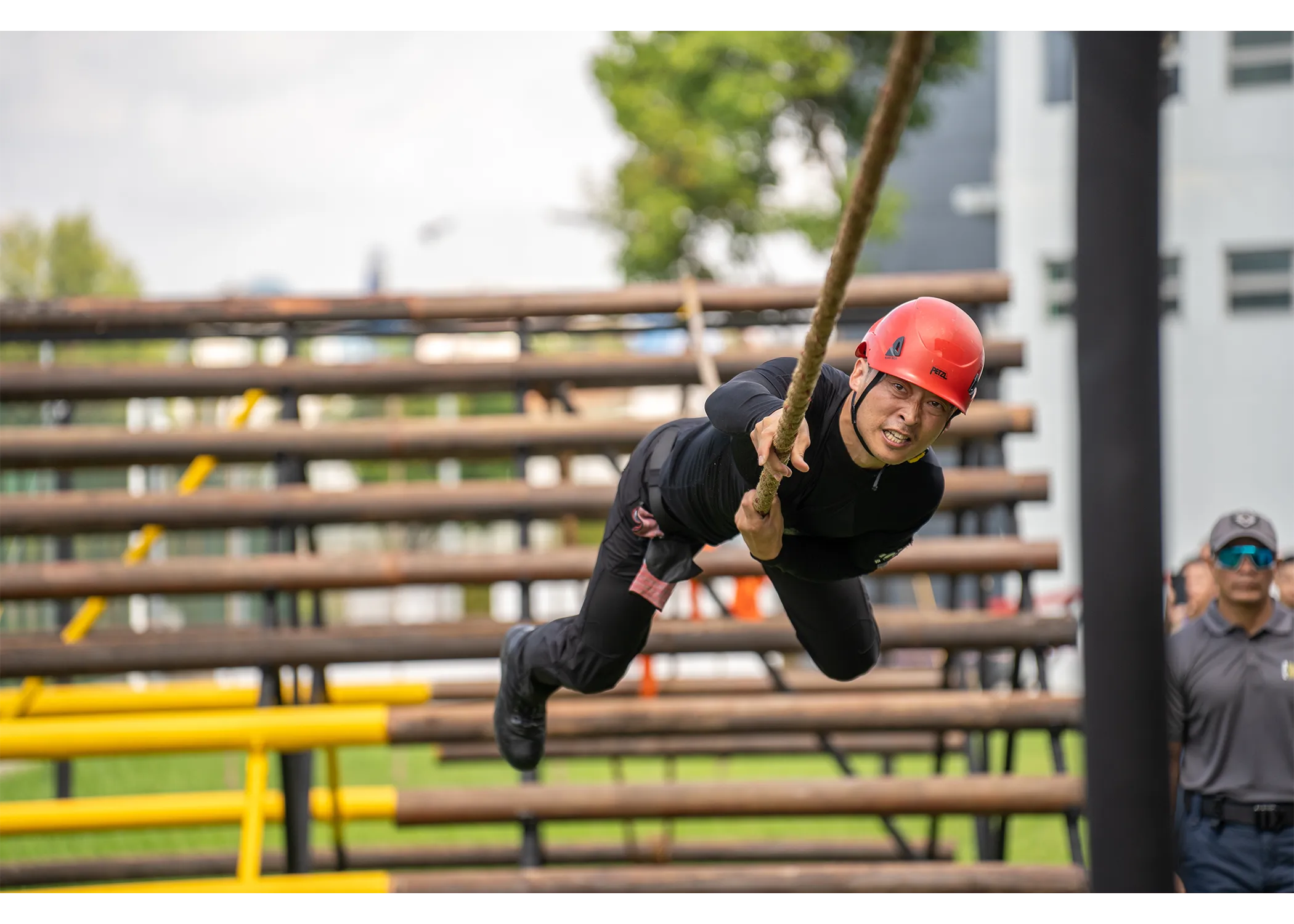 An officer looking halfway through the commando rope station, looking determined to cross it