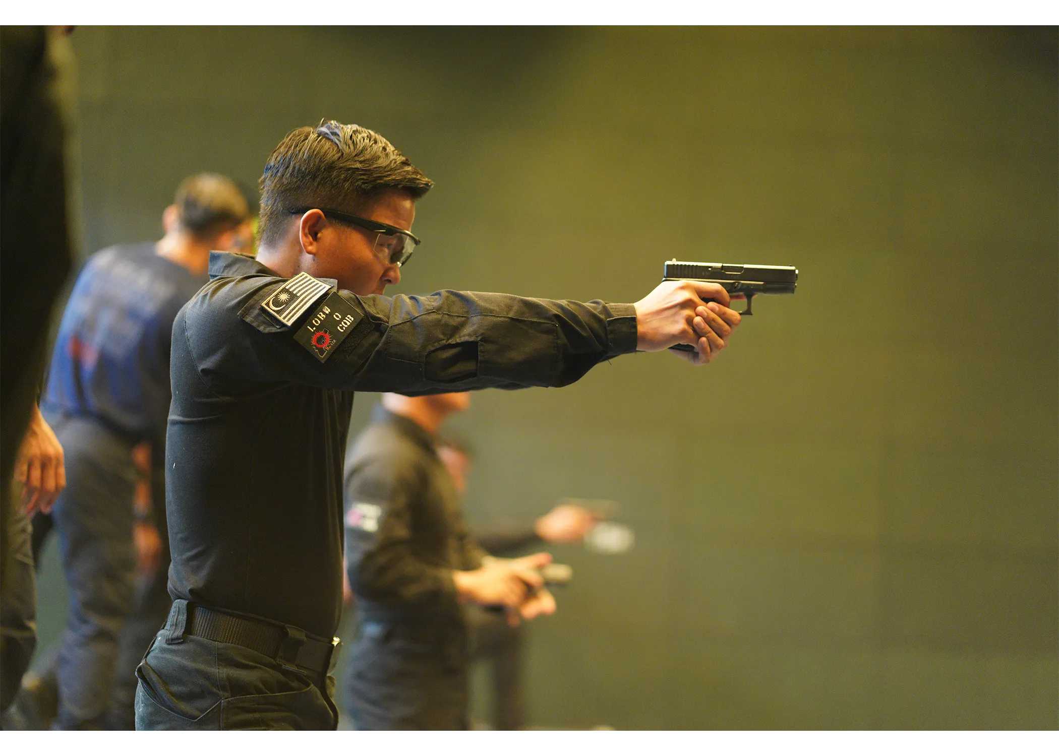 An officer pointing his pistol down range.