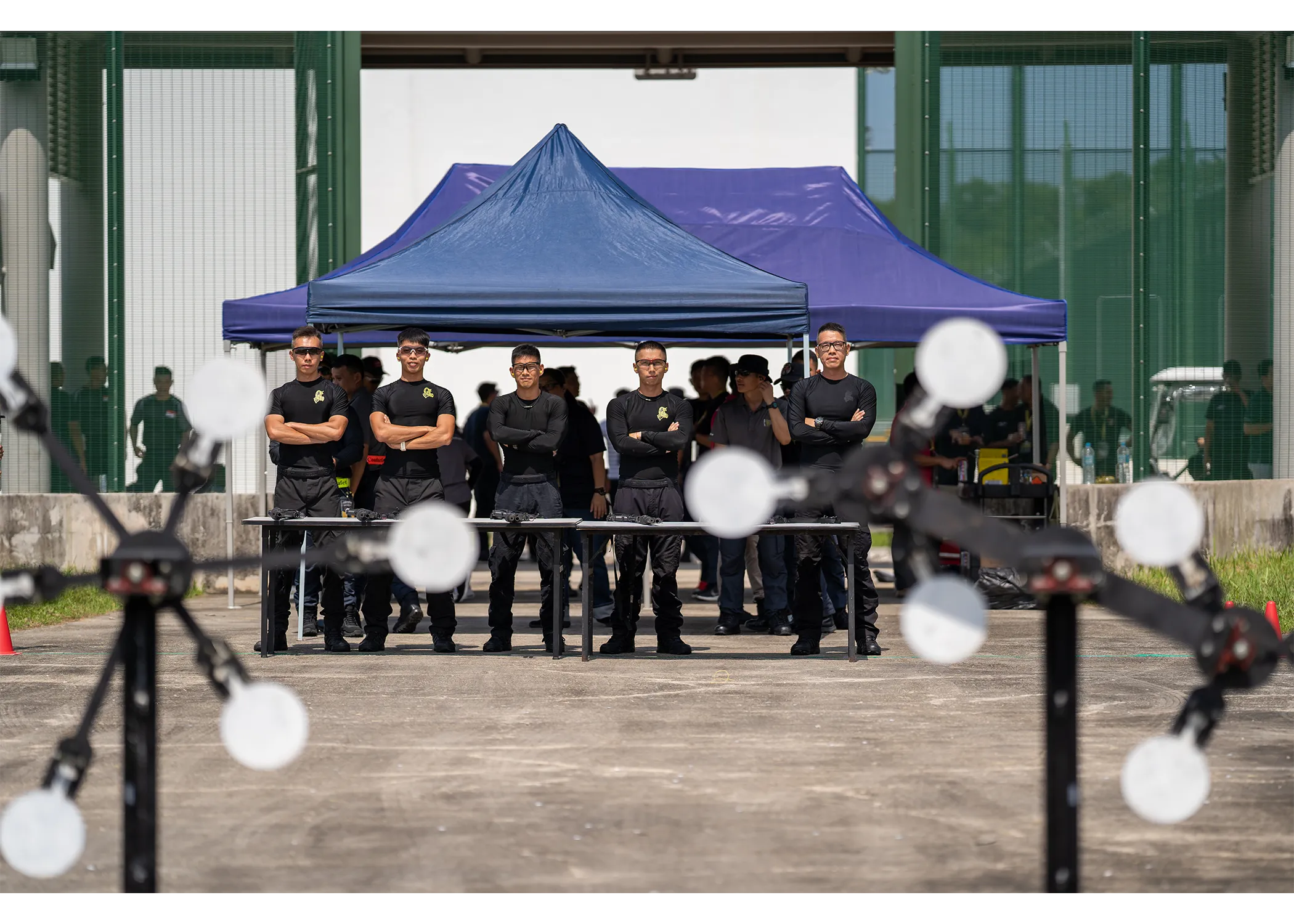 A group of officers posing for a group photograph behind their rifle at the outdoor shooting event station.