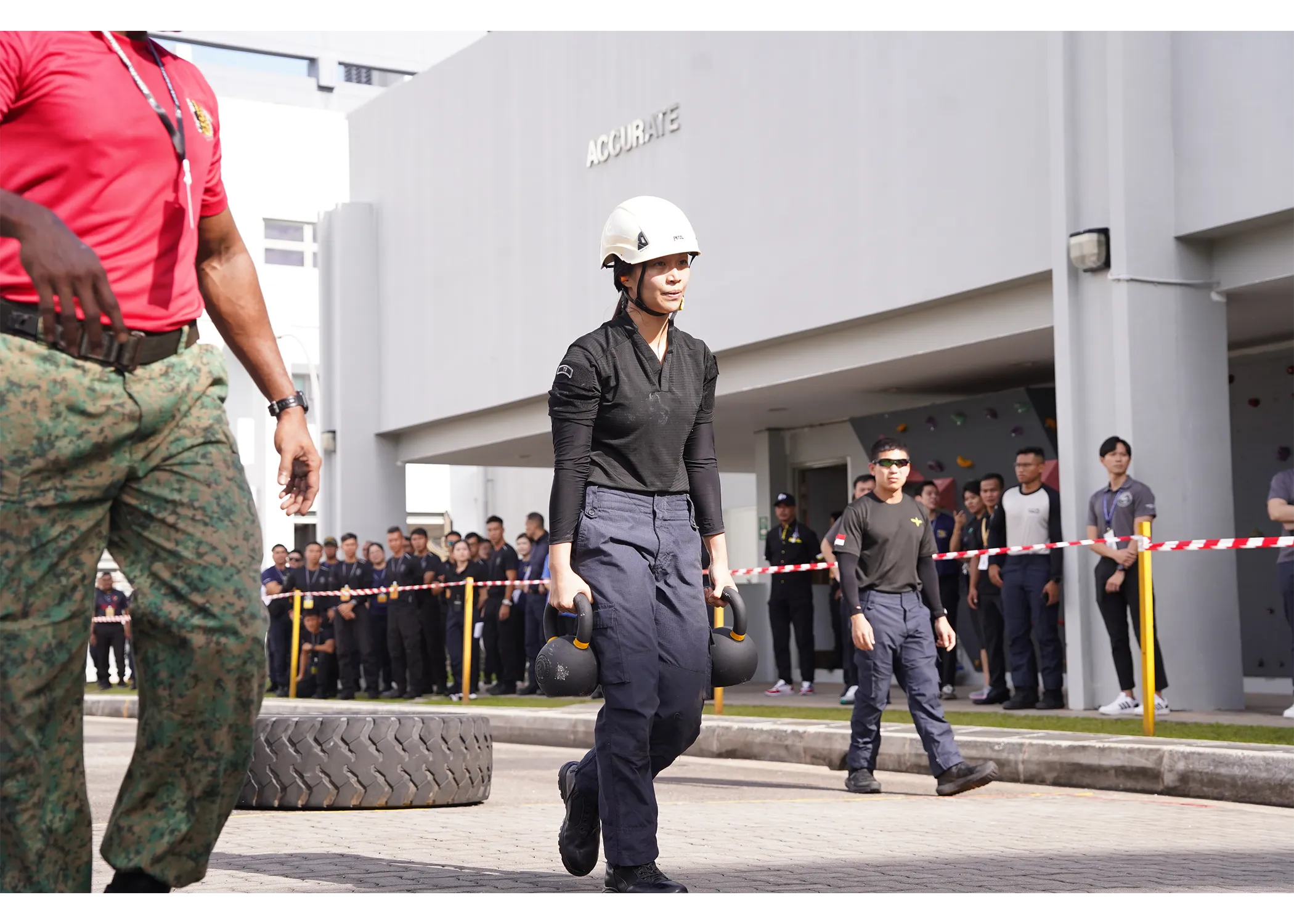 A female officer doing the farmer walk event with a kettlebell on each hand