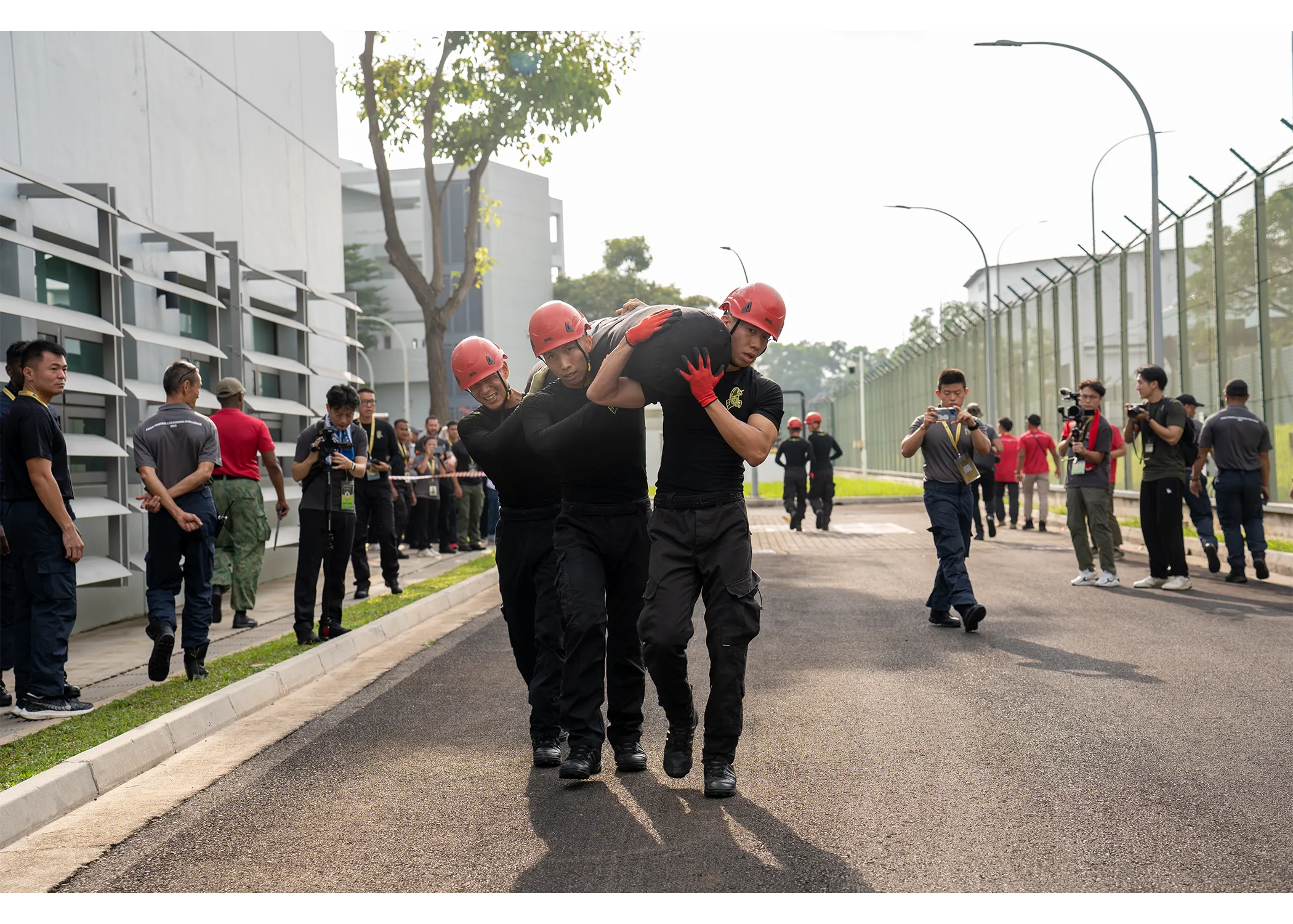 A group of three officers walking with a heavy sandbag log over their shoulders 